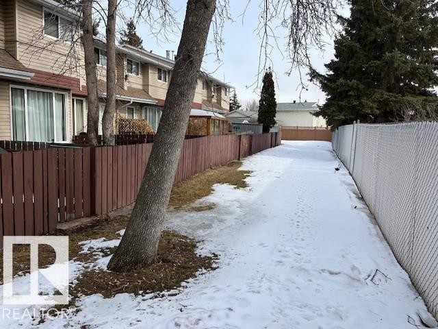 The property features a private fenced yard with a brown wooden fence, a mature tree, and a paved pathway - 350 Clareview Road, Edmonton, AB - Outdoor
