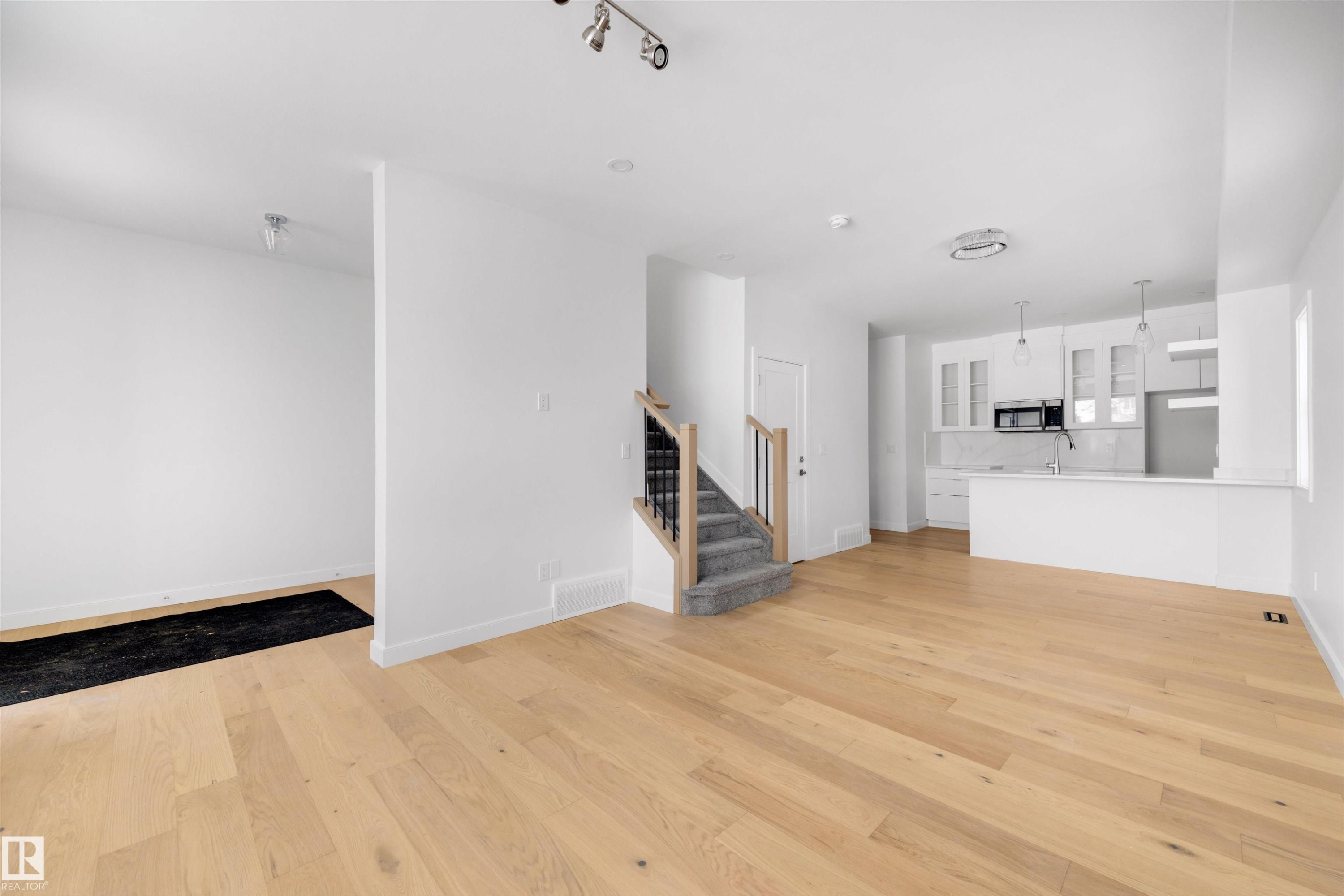 Bright and open concept living area featuring light-toned hardwood flooring, white walls, and recessed lighting - 7927 112S Avenue, Edmonton, AB - Indoor Photo Showing Kitchen