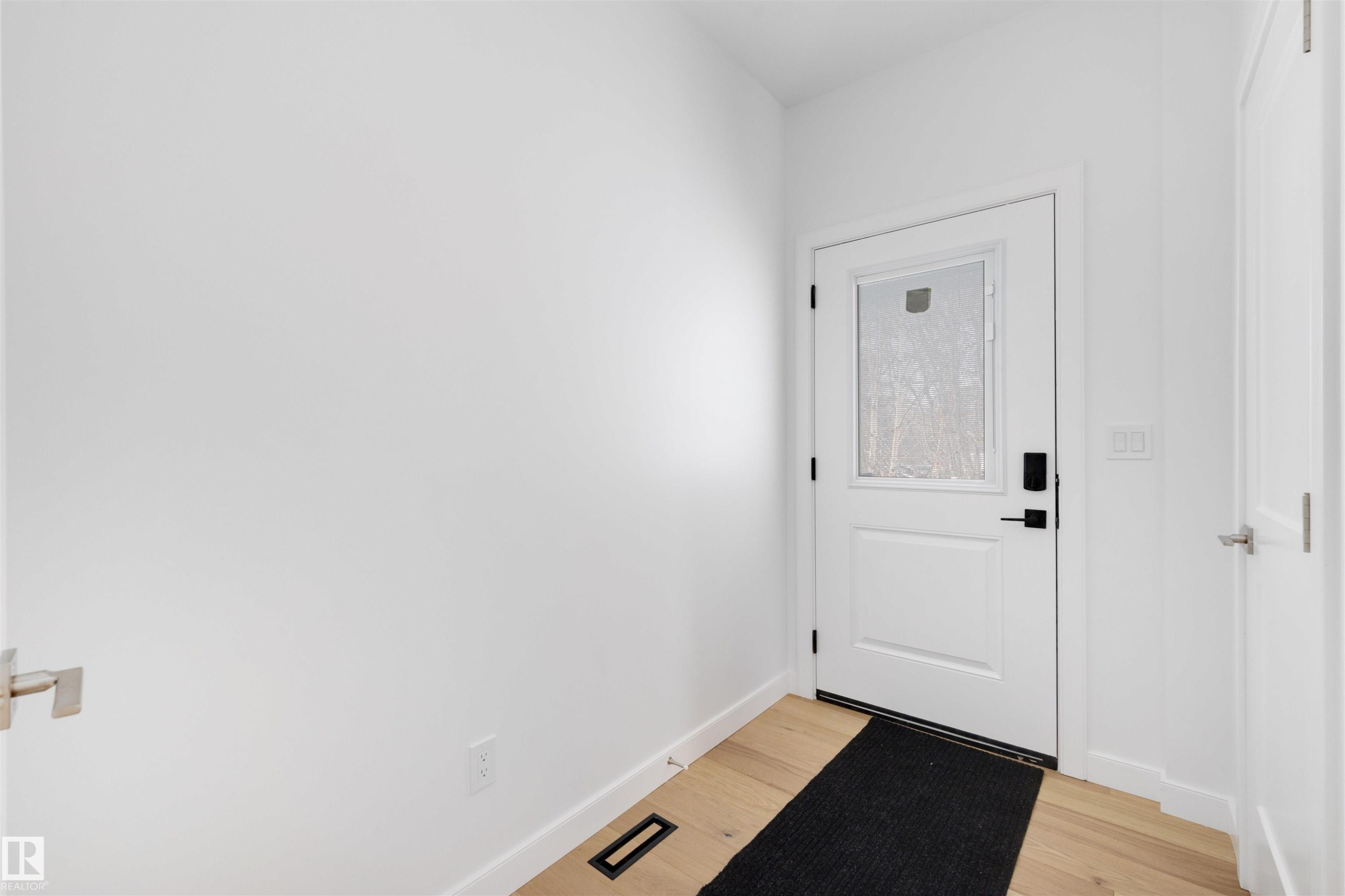 The property features light hardwood floors and a white door with a window - 7927 112S Avenue, Edmonton, AB - Indoor Photo Showing Other Room