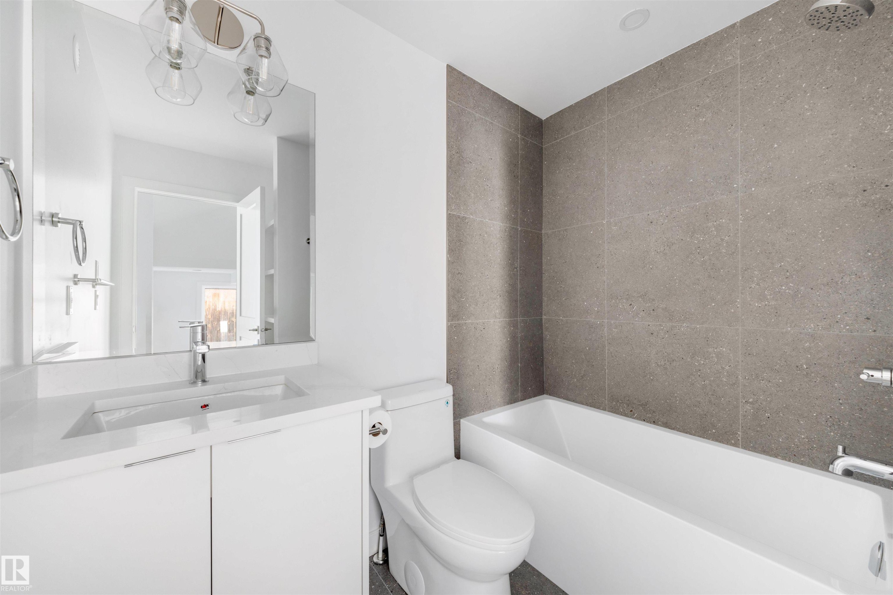 Contemporary bathroom featuring a white vanity with an integrated sink, a rectangular mirror, and a modern light fixture - 7927 112S Avenue, Edmonton, AB - Indoor Photo Showing Bathroom