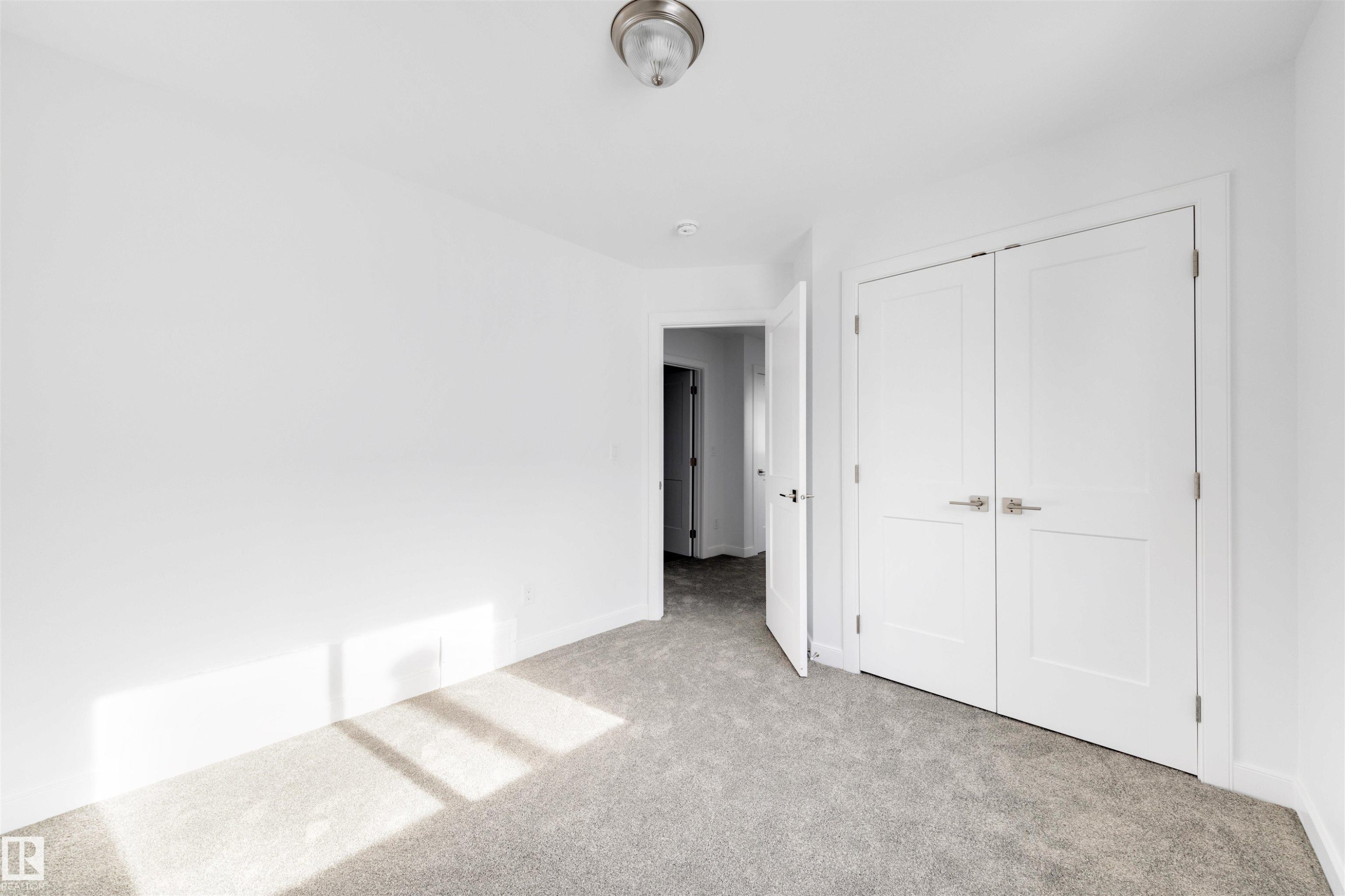 The room features neutral gray carpeting, white walls, and a white double door closet - 7927 112S Avenue, Edmonton, AB - Indoor Photo Showing Other Room