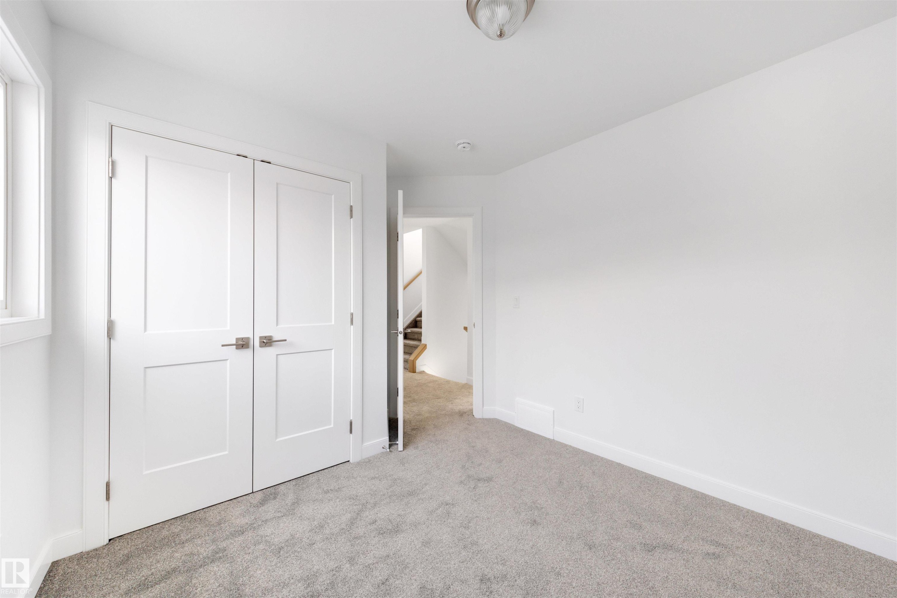 This space features light grey carpeting, white walls, and a window providing natural light - 7927 112S Avenue, Edmonton, AB - Indoor Photo Showing Other Room