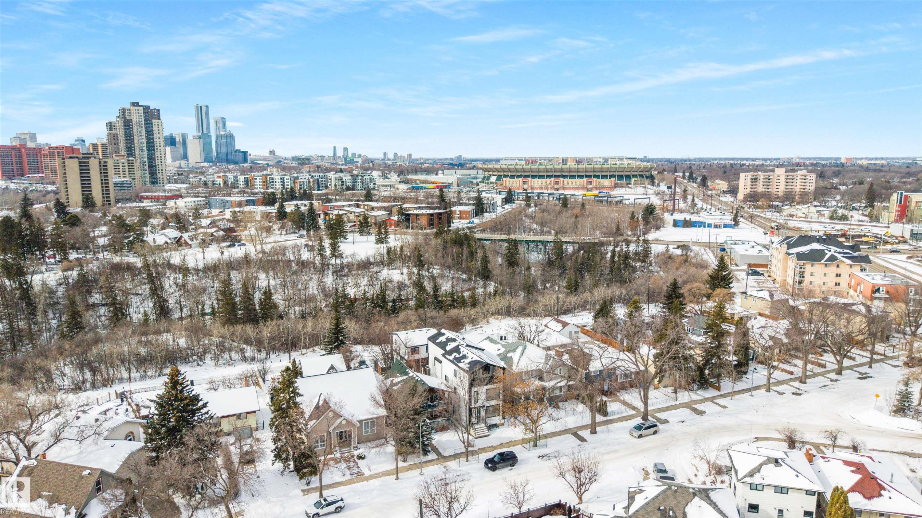 Aerial view showcasing the neighborhood with residential properties, city buildings, and a stadium in the distance - 7927 112S Avenue, Edmonton, AB - Outdoor With View