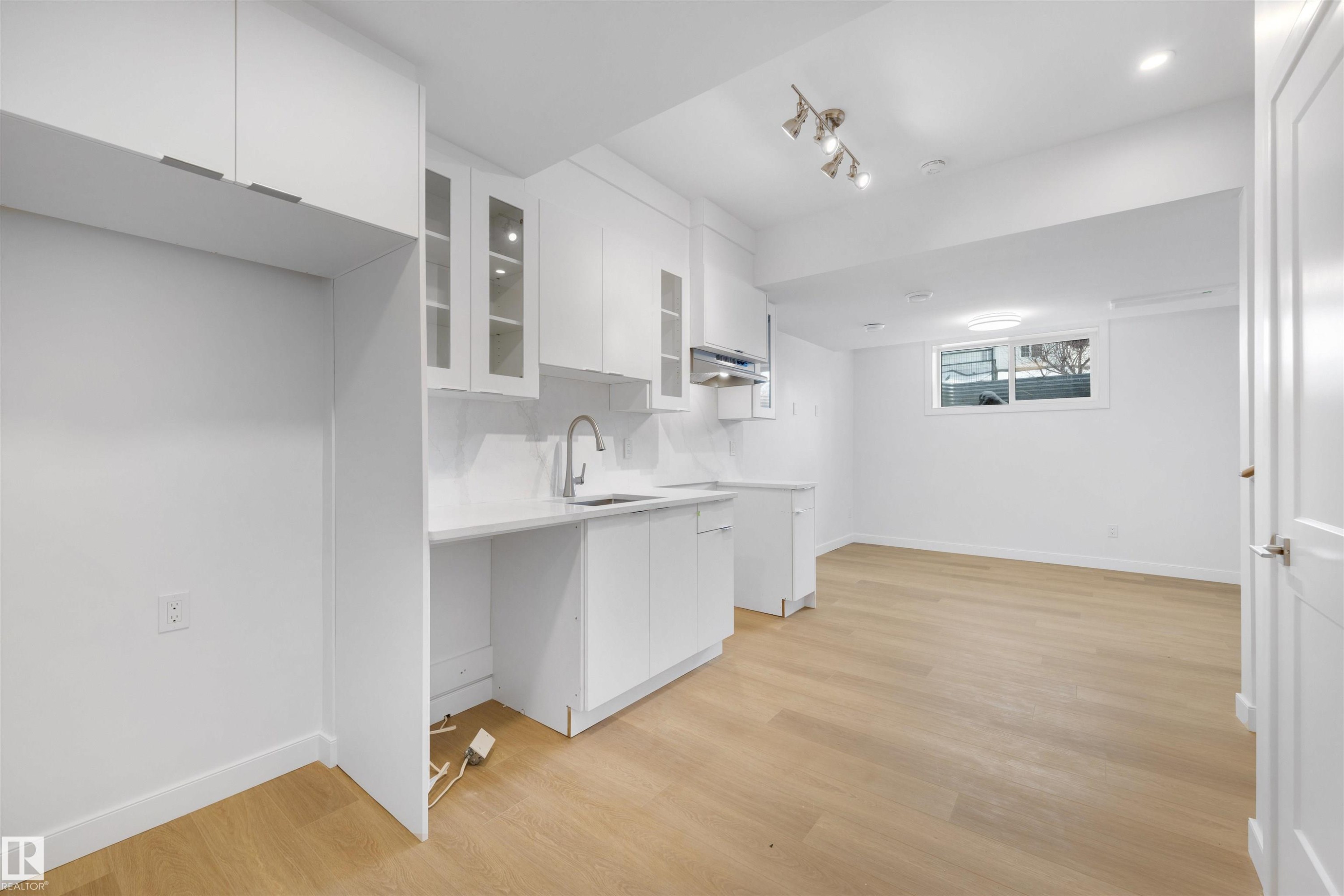 Kitchenette featuring white cabinetry, a sink with a gooseneck faucet, and light-toned flooring - 7927 112S Avenue, Edmonton, AB - Indoor