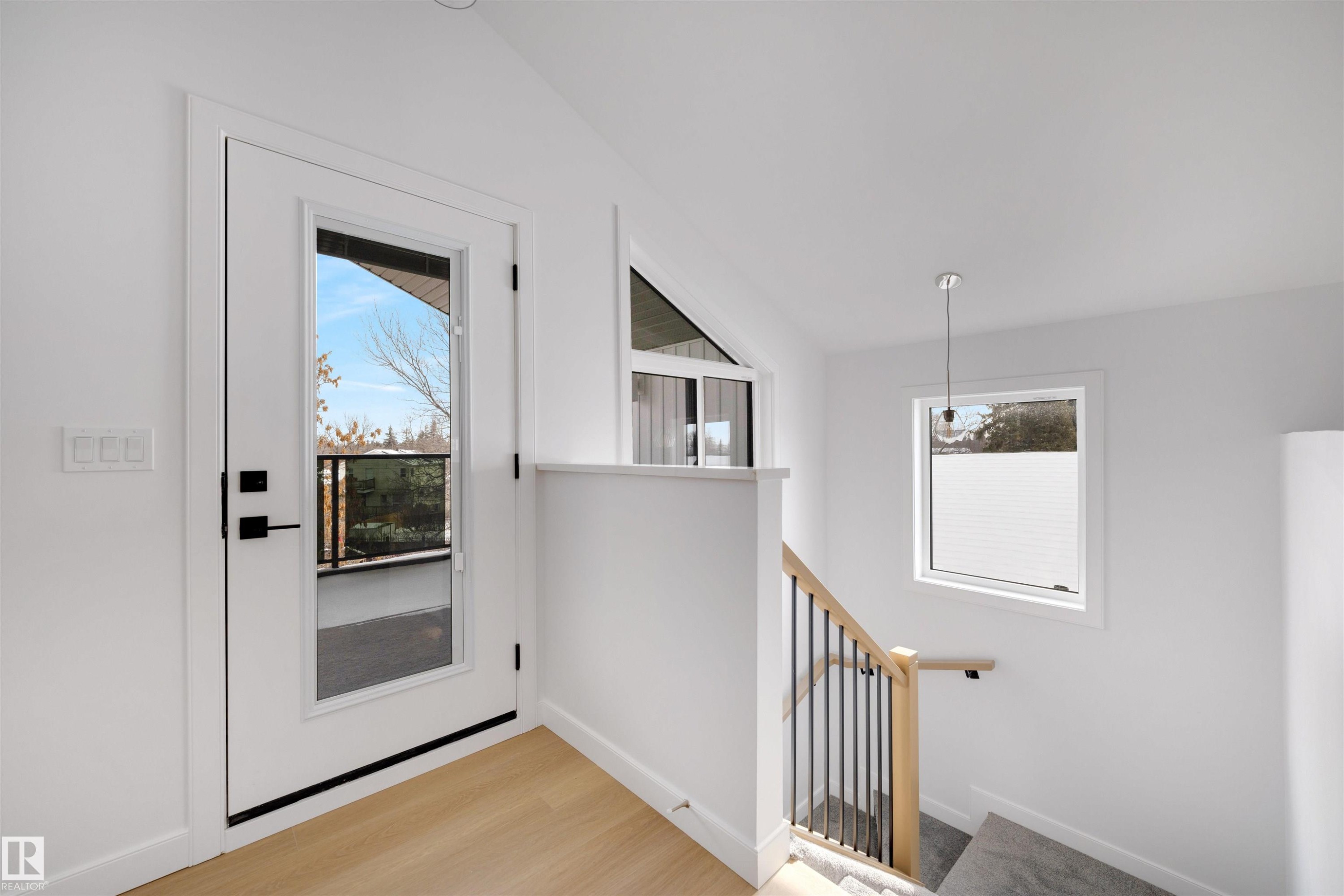 Entryway featuring light-toned flooring, a full-view glass door with black hardware, and a staircase with a natural wood handrail and black balusters - 7927 112S Avenue, Edmonton, AB - Indoor Photo Showing Other Room