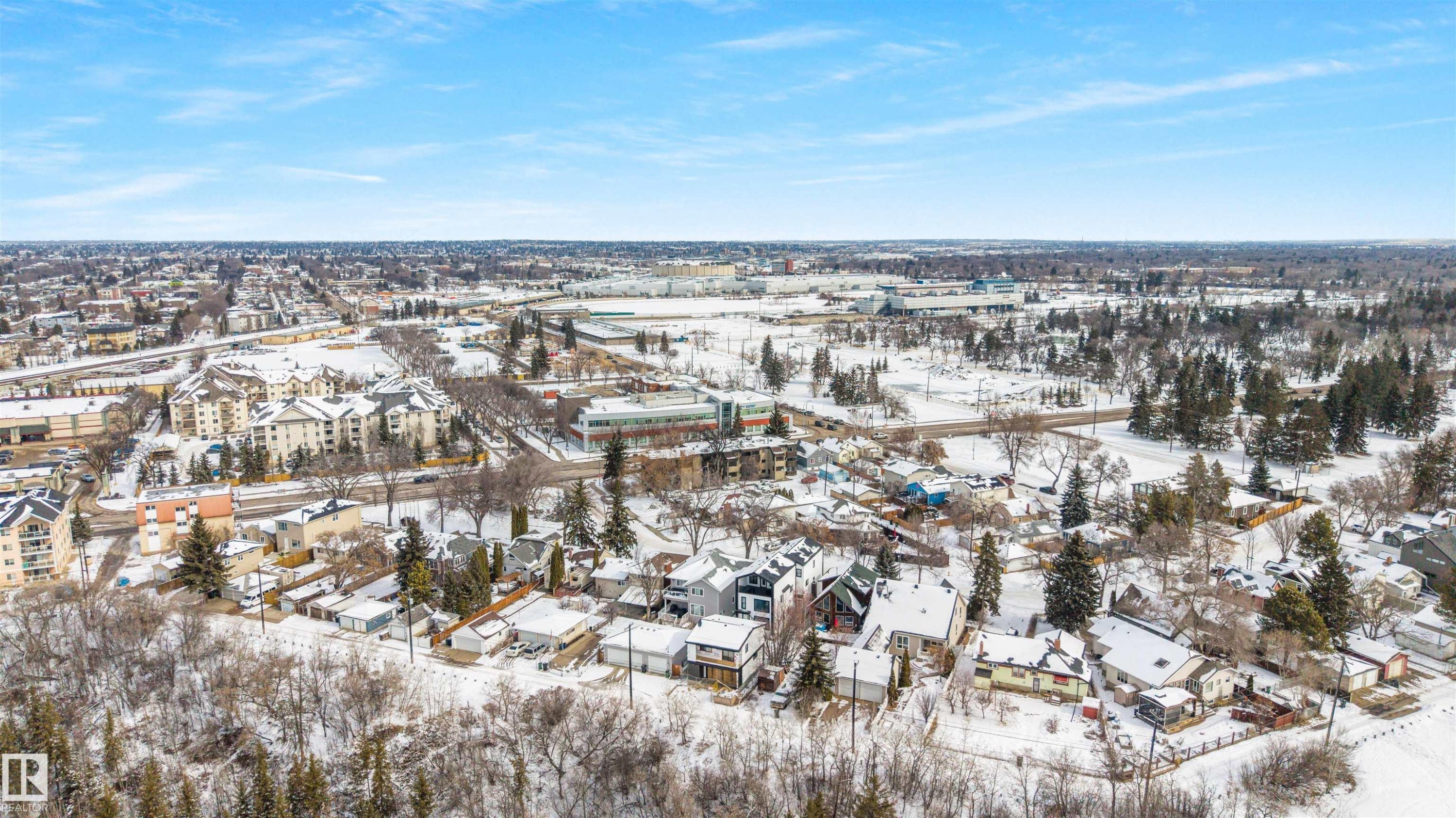 The property is situated within a community featuring various residential buildings and abundant mature trees, with a clear sky overhead - 7927 112S Avenue, Edmonton, AB - Outdoor With View