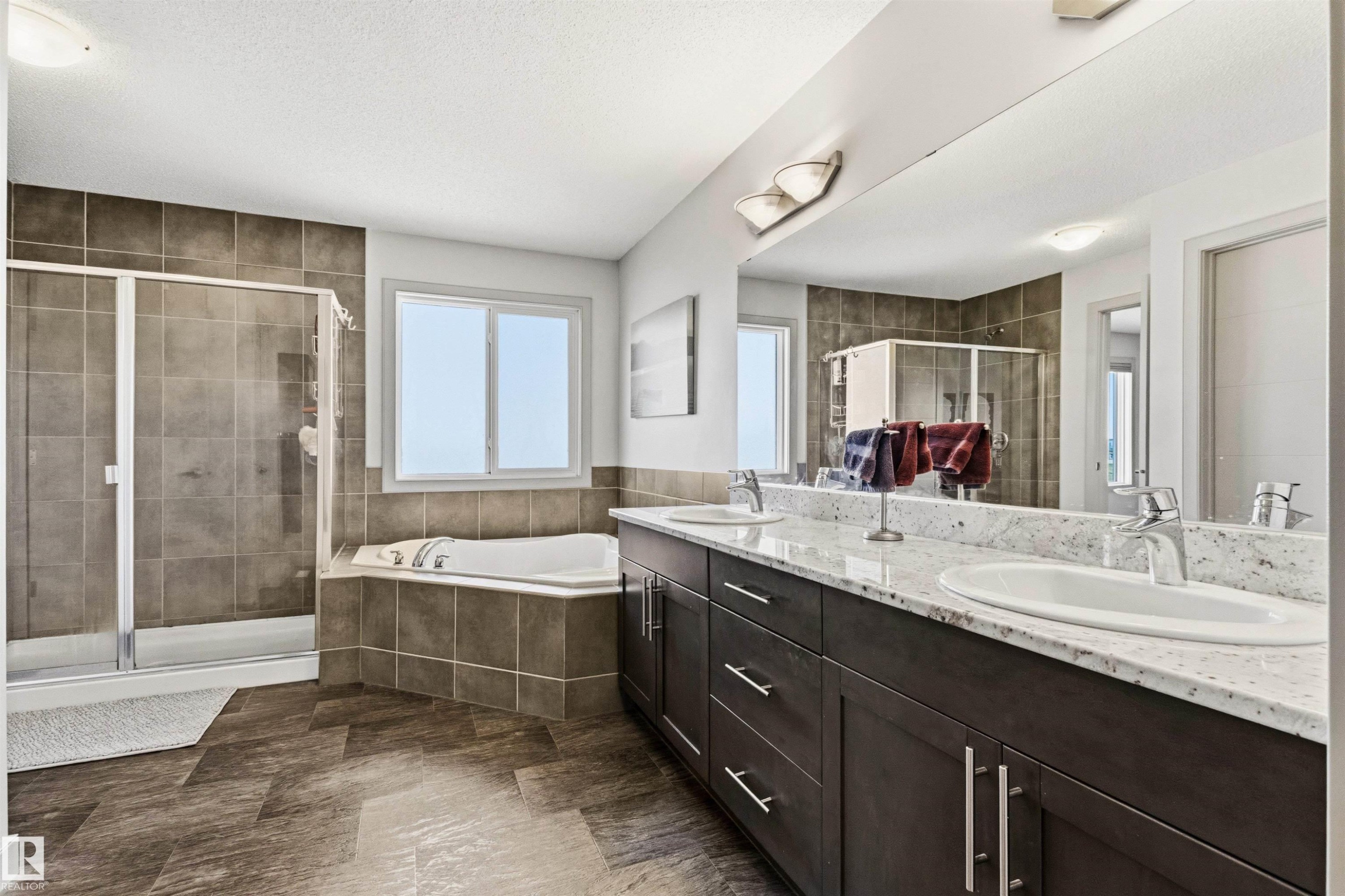 Bathroom featuring a full-width mirror, granite top vanity with two sinks, and a large soaker tub. - 7343 Armour Crescent, Edmonton, AB - Indoor Photo Showing Bathroom