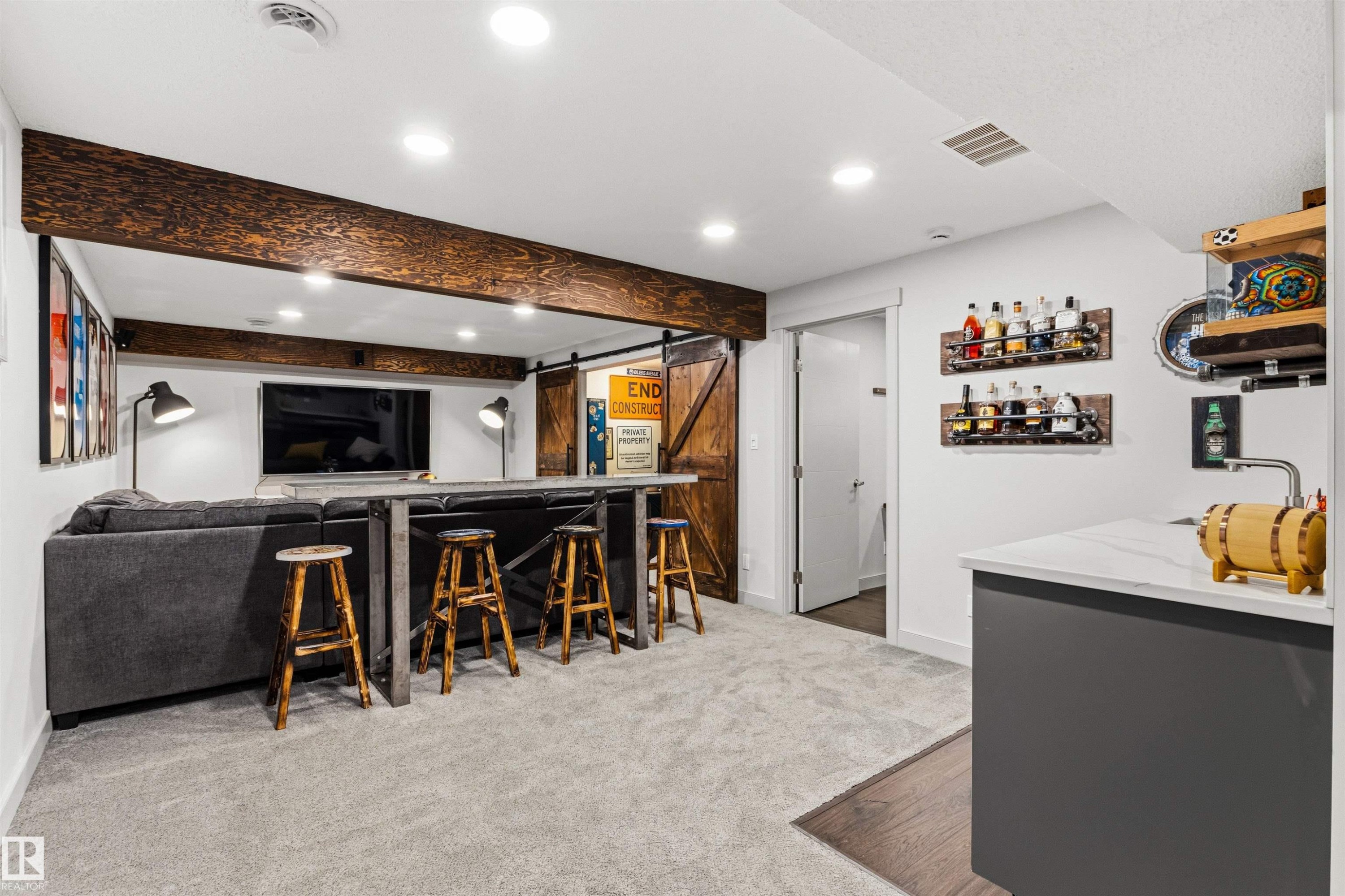 Finished basement featuring a built-in bar with seating, recessed lighting, and a wood-finish barn door - 7343 Armour Crescent, Edmonton, AB - Indoor