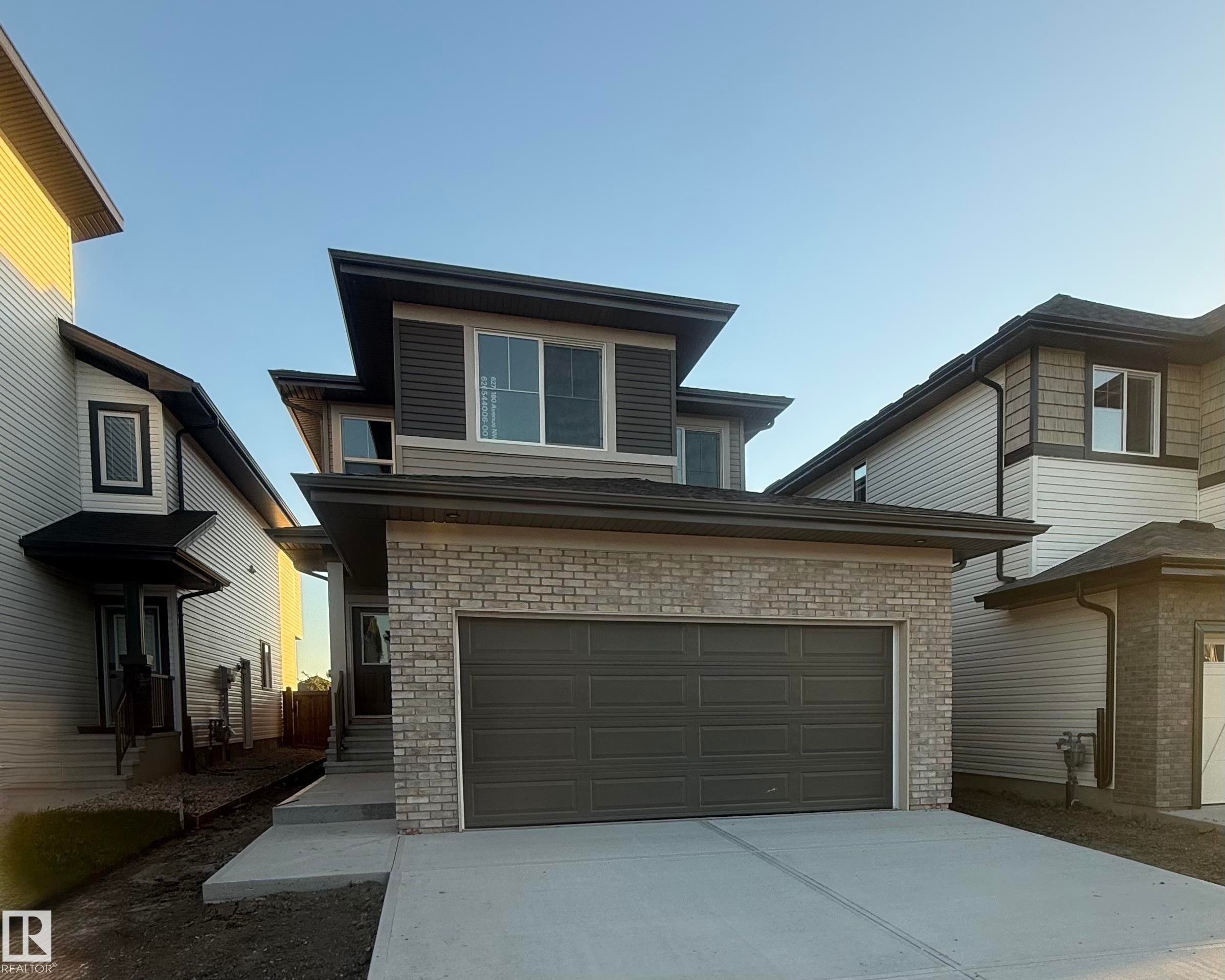Contemporary exterior with a brick facade, multi-pane windows, attached garage, and concrete driveway - 6271 180 Avenue Nw, Edmonton, AB