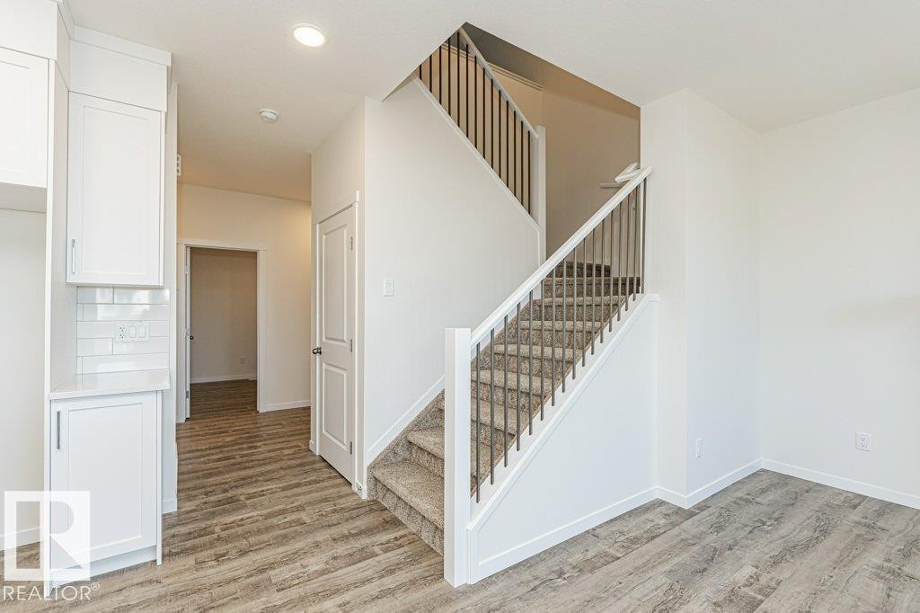 Contemporary staircase featuring carpeted treads and dark metal balusters - 6271 180 Avenue Nw, Edmonton, AB