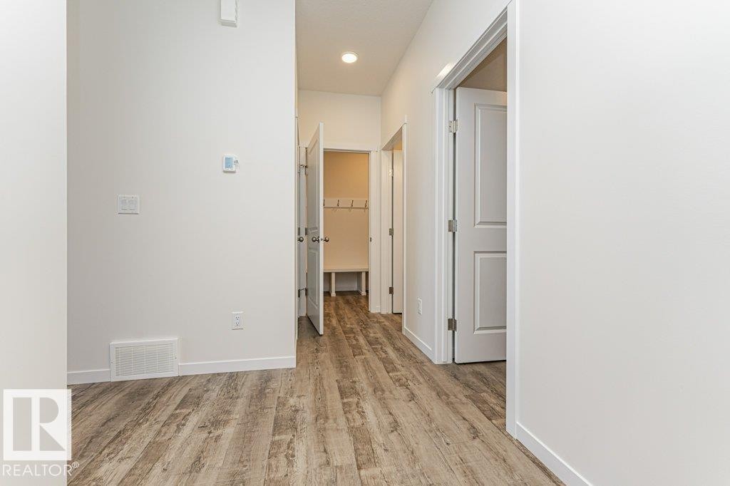 Hallway featuring wood-finish flooring, white walls, and recessed lighting - 6271 180 Avenue Nw, Edmonton, AB
