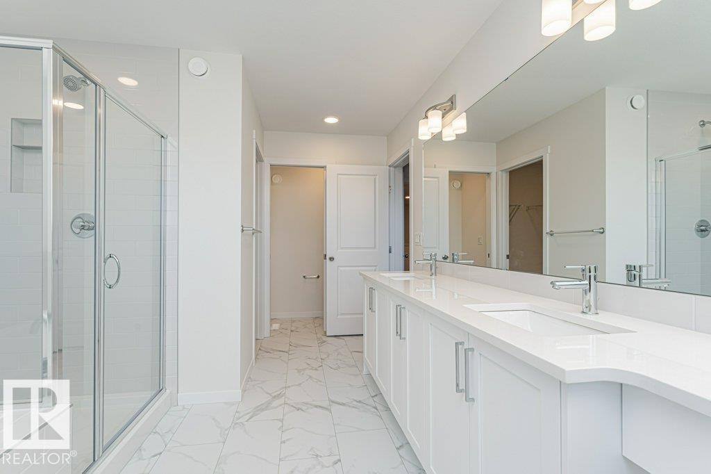 Spacious bathroom featuring a double vanity with stone countertops, undermount sinks, and chrome fixtures - 6271 180 Avenue Nw, Edmonton, AB