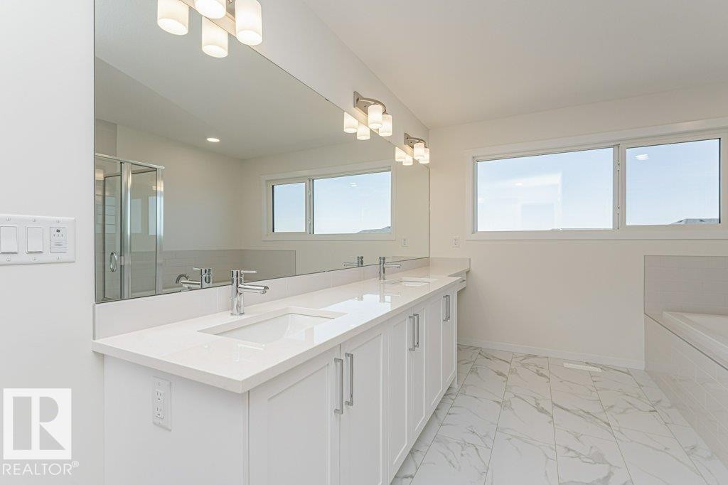 Modern bathroom featuring a double vanity with white cabinetry, polished chrome faucets, and a continuous mirror - 6271 180 Avenue Nw, Edmonton, AB
