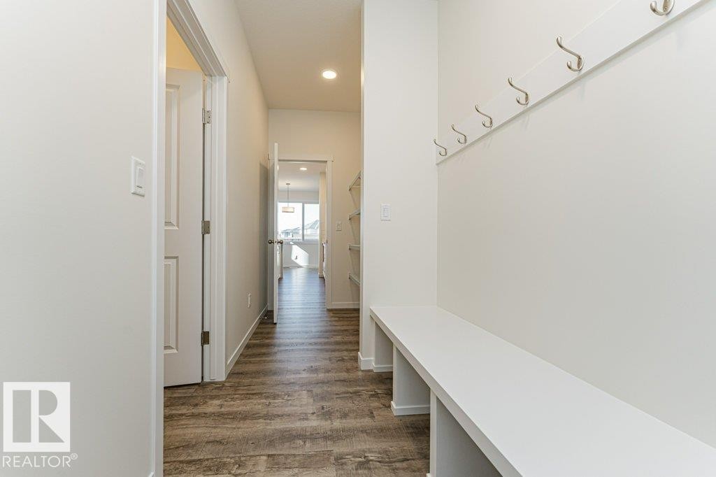 Entryway featuring wood-finish flooring, recessed lighting, white walls, built-in bench seating, and wall-mounted coat hooks - 6271 180 Avenue Nw, Edmonton, AB