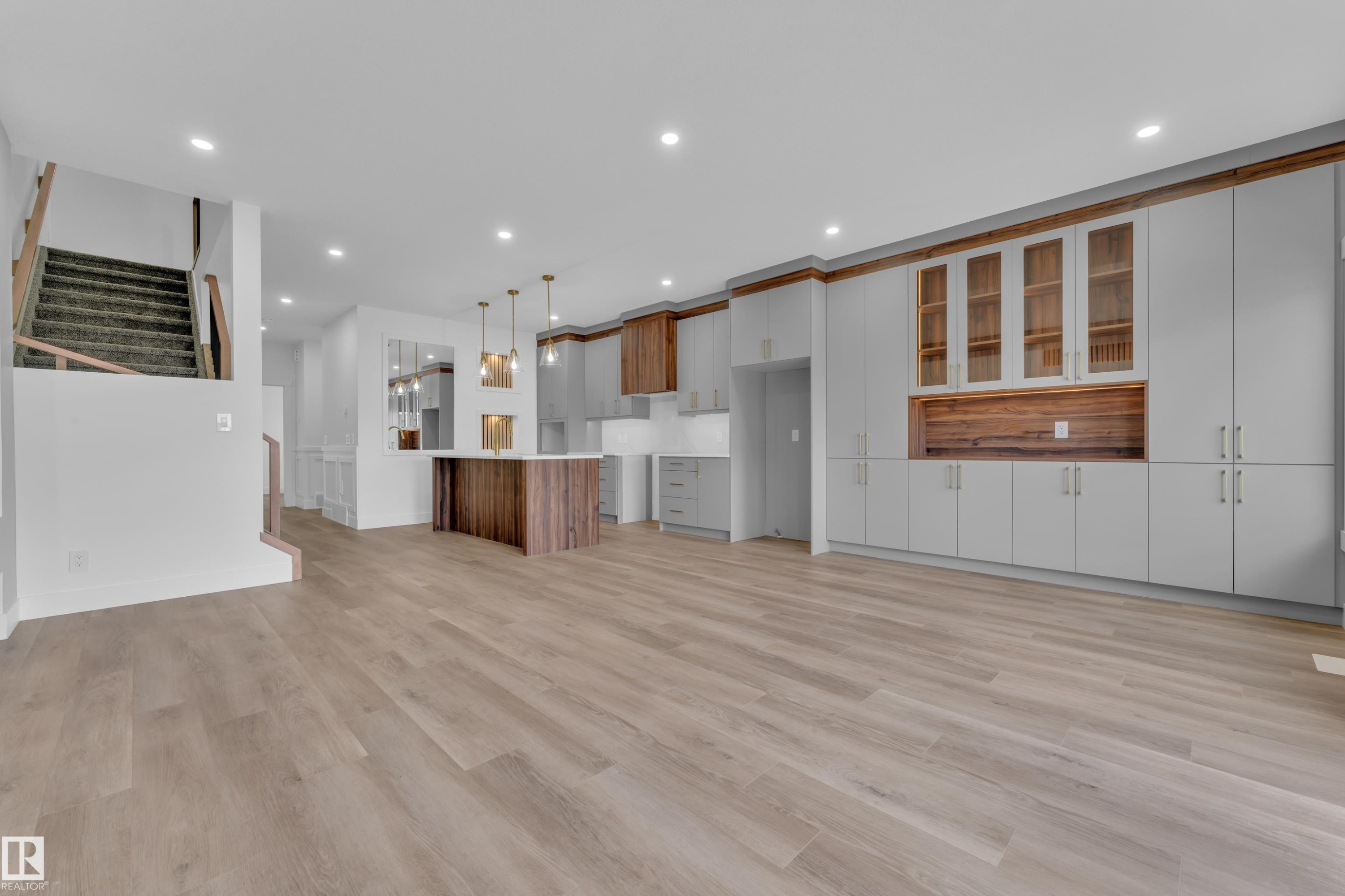 Open-concept living area featuring wide plank wood-finish flooring, recessed lighting, and a modern kitchen with a wood-finish island - 3116 8 Avenue, Edmonton, AB