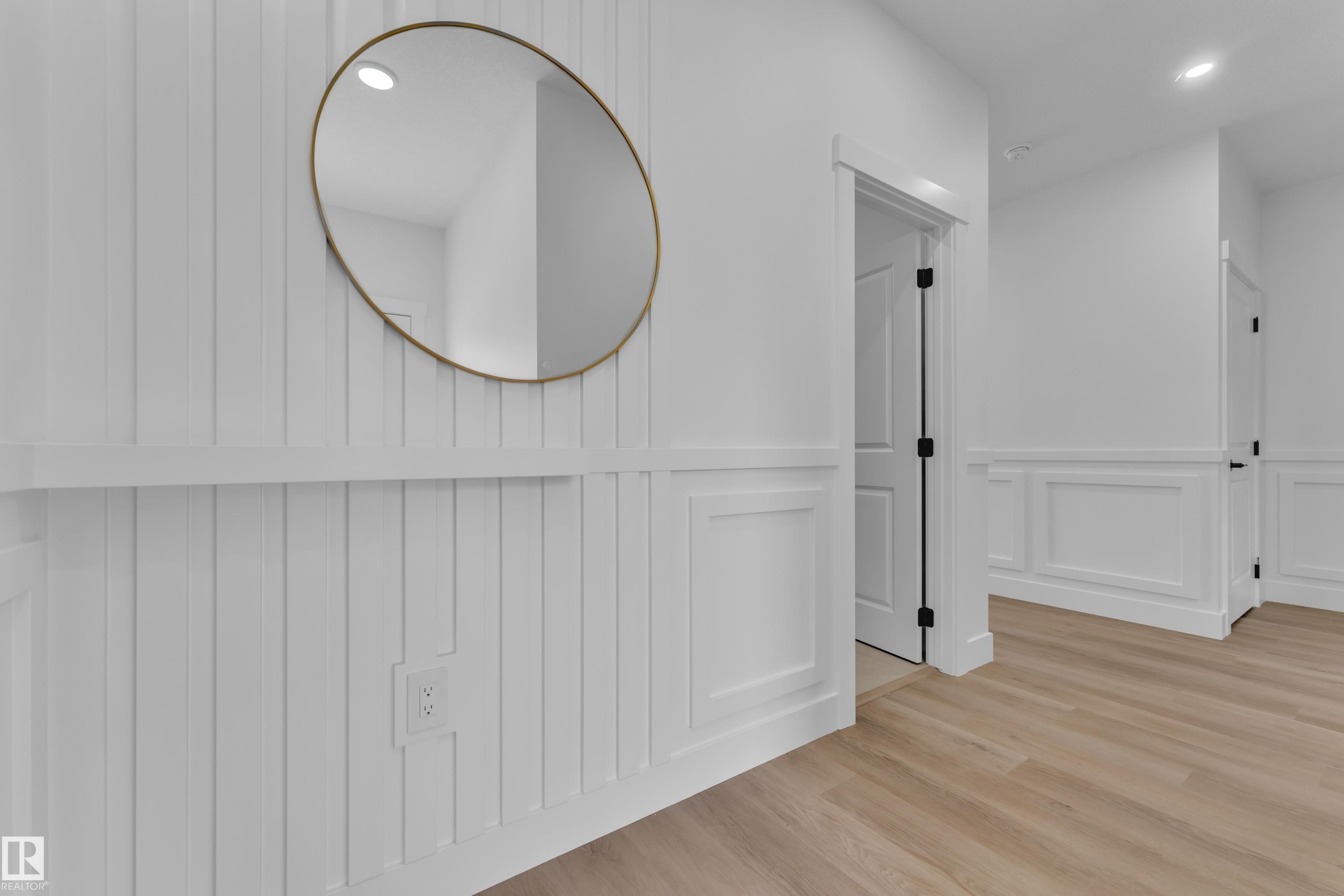White wainscoting and board and batten wall details, light wood-finish flooring, recessed lighting, and black hardware on interior doors - 3116 8 Avenue, Edmonton, AB