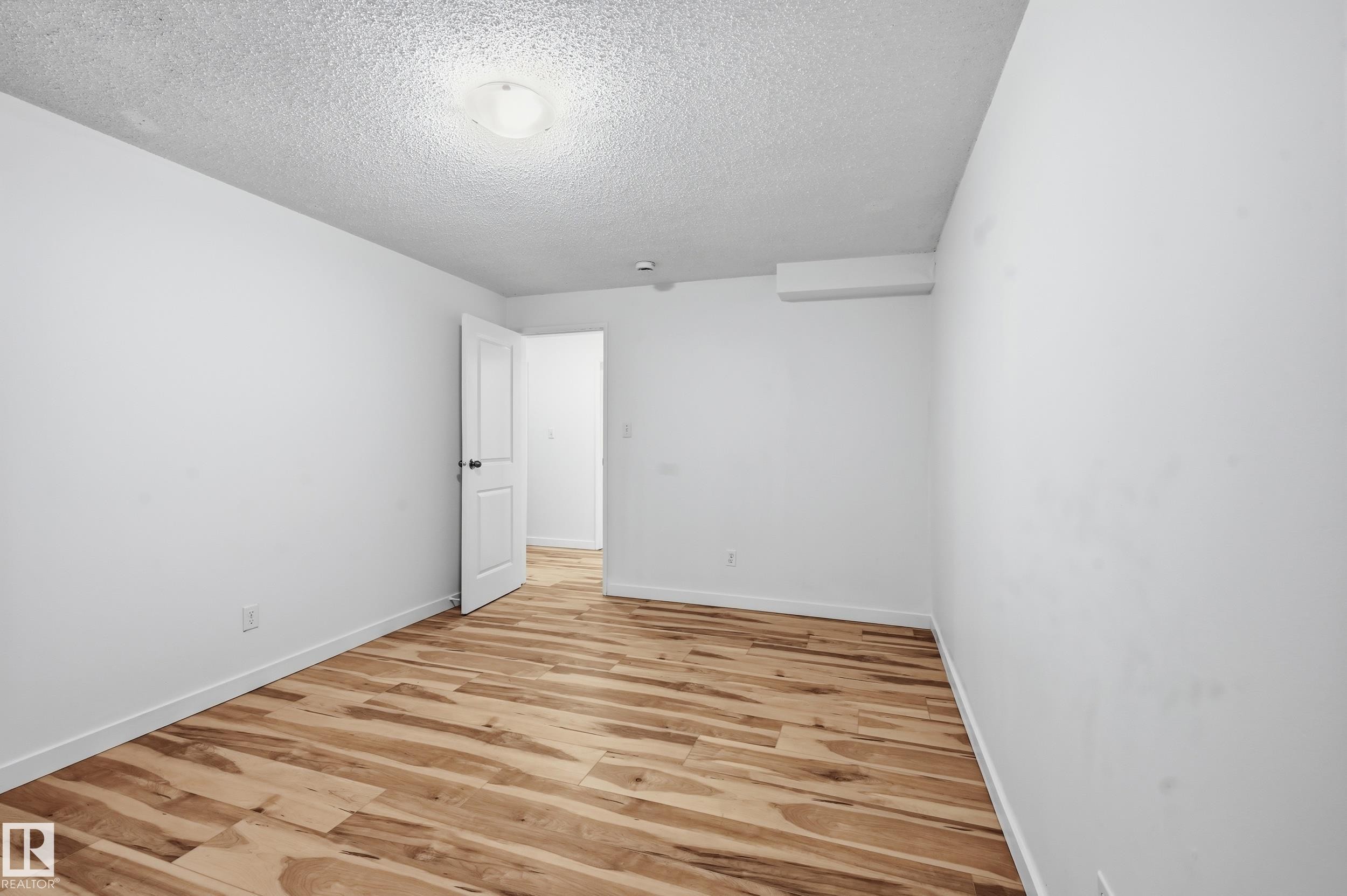 Room featuring wood-finish flooring, white baseboards, and bright white walls - 13903 87 Street, Edmonton, AB - Indoor Photo Showing Other Room