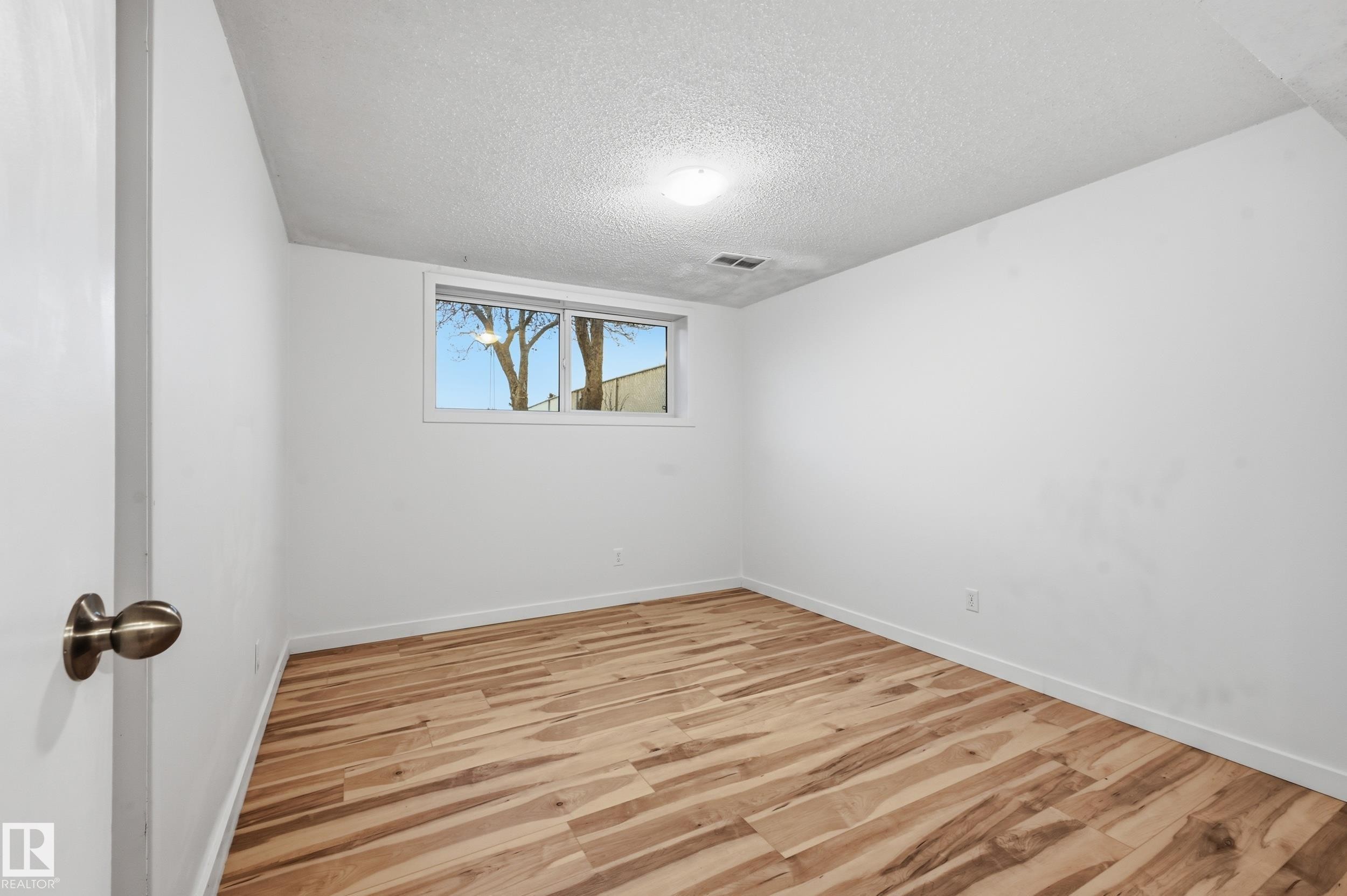 Room featuring wood-finish flooring, white baseboards, and a window with white trim - 13903 87 Street, Edmonton, AB - Indoor Photo Showing Other Room