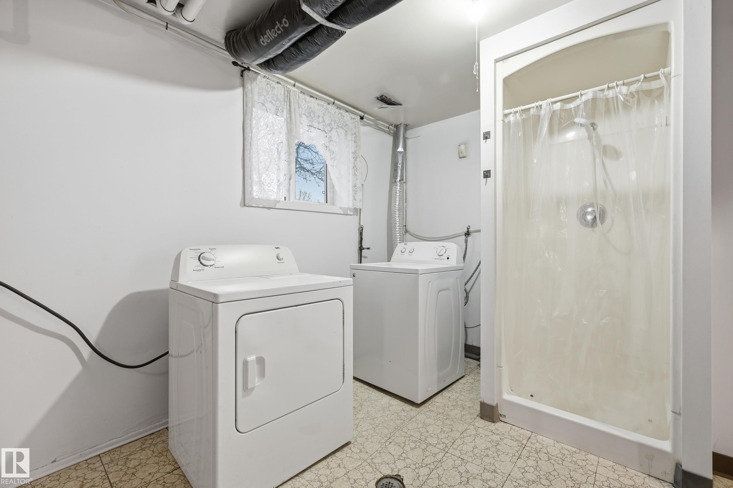 Laundry area with a stand-up shower, window, and patterned tile flooring - 13903 87 Street, Edmonton, AB - Indoor Photo Showing Laundry Room