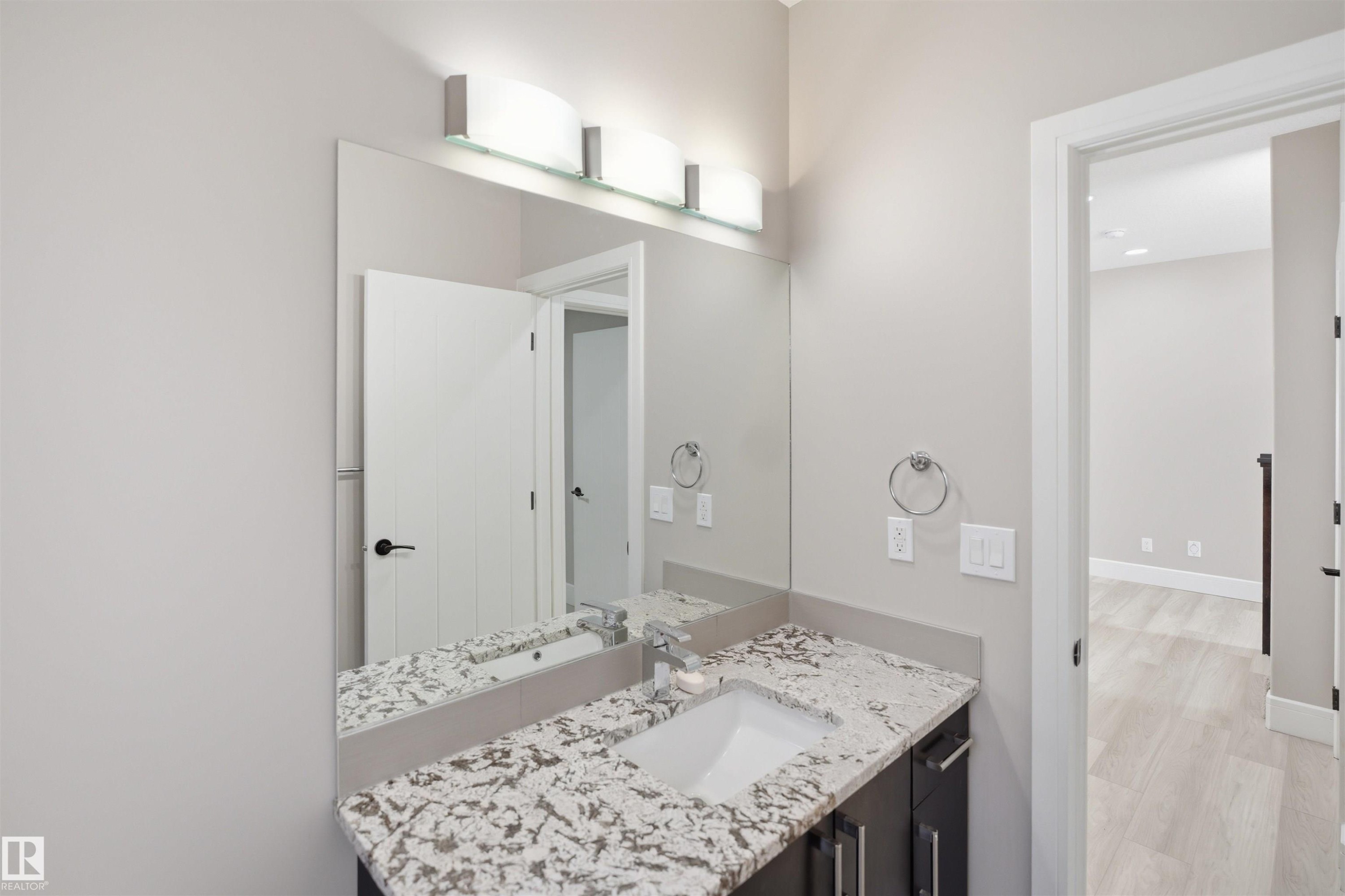 Vanity featuring a patterned countertop, undermount sink, and dark wood-finish cabinetry - 2256 Cameron Ravine Court, Edmonton, AB - Indoor Photo Showing Bathroom