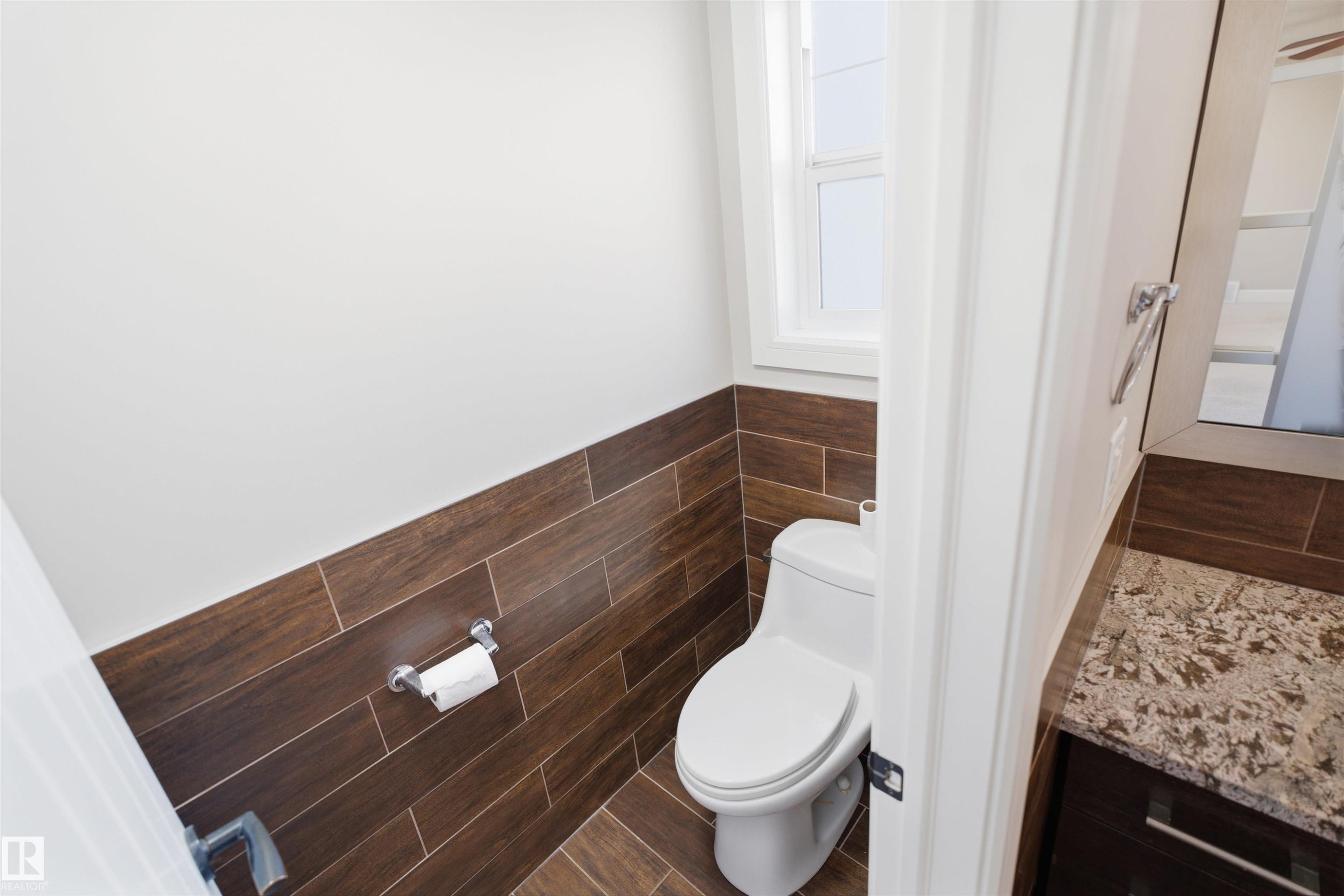 Compact powder room featuring wood-finish tile flooring, a coordinating wood-finish wainscoting, and a single-pane window - 2256 Cameron Ravine Court, Edmonton, AB - Indoor Photo Showing Bathroom