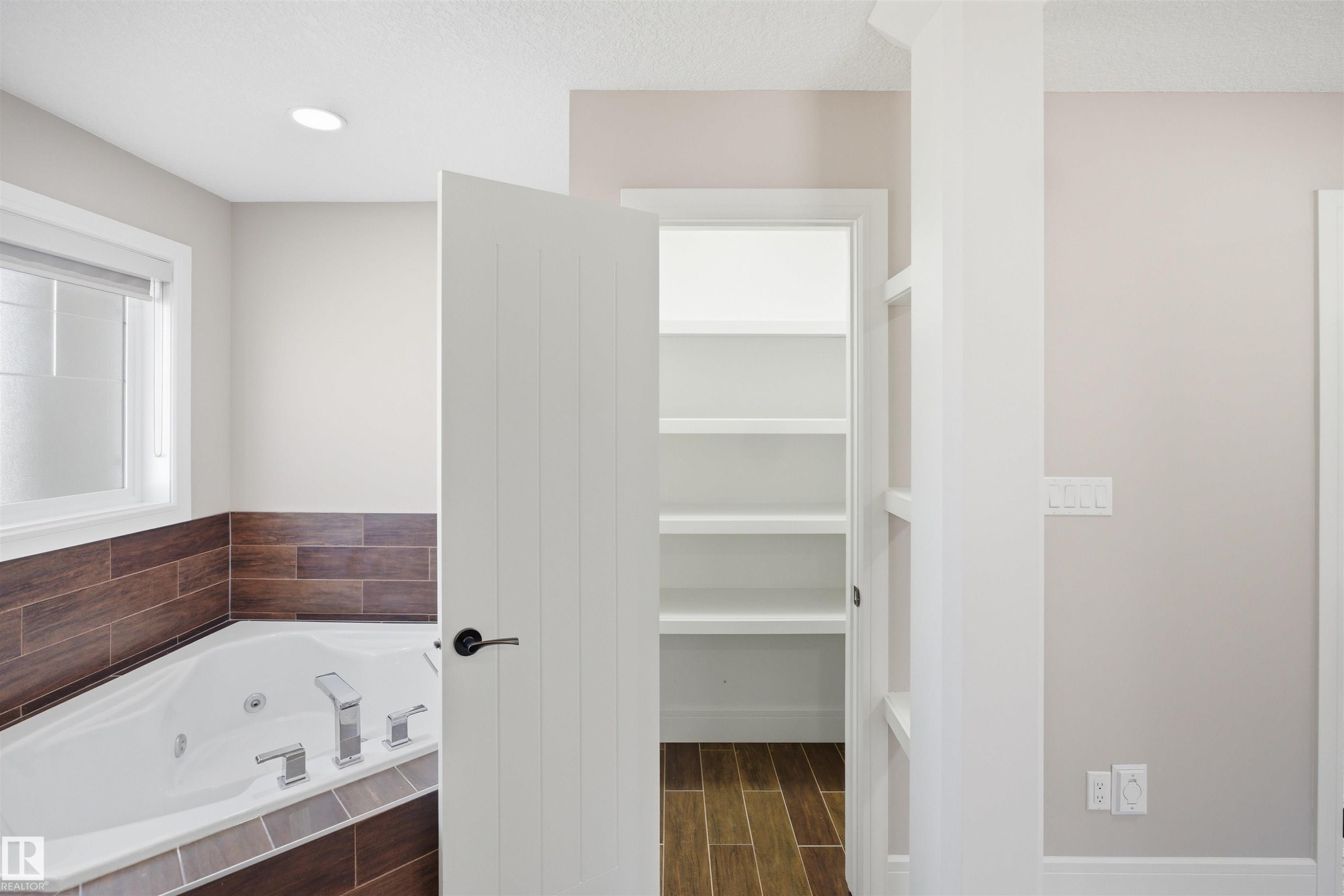 Corner soaking tub with tiled surround featuring wood-finish accent tiles - 2256 Cameron Ravine Court, Edmonton, AB - Indoor Photo Showing Bathroom