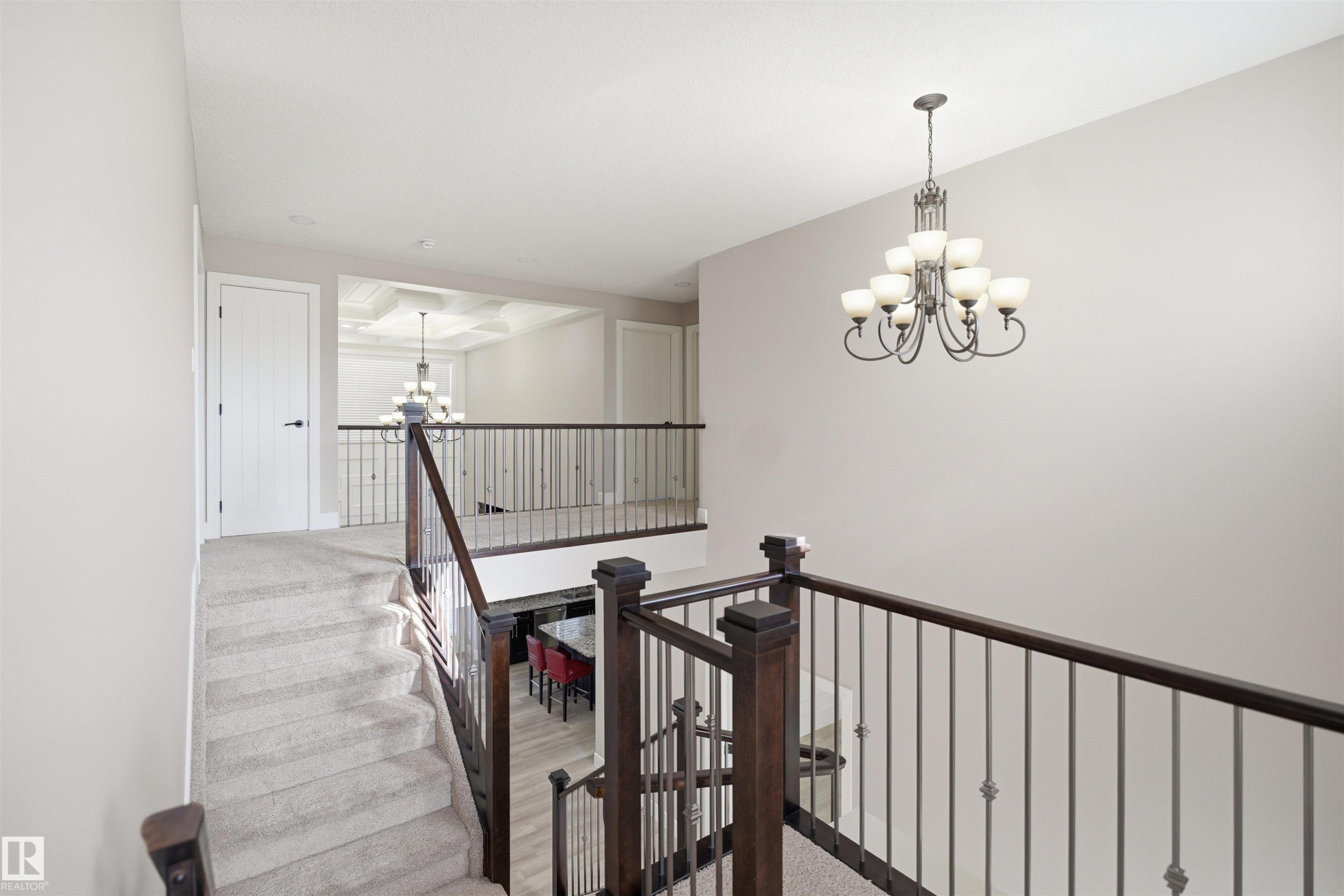 Carpeted staircase with dark wood newel posts and railings, complemented by iron balusters - 2256 Cameron Ravine Court, Edmonton, AB - Indoor Photo Showing Other Room