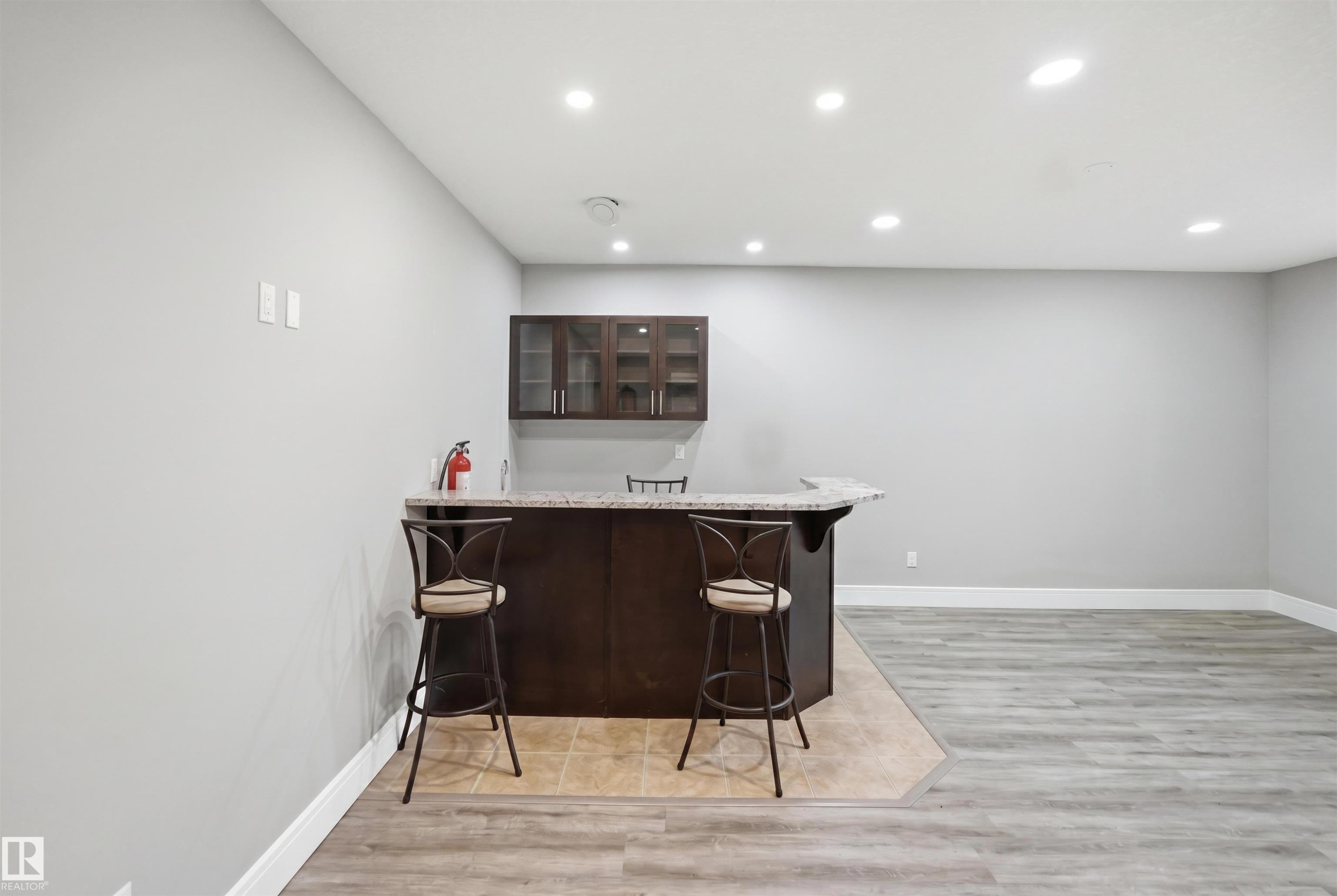 Built-in bar with dark wood cabinetry, a light-colored countertop, and integrated glass-front upper cabinets - 2256 Cameron Ravine Court, Edmonton, AB - Indoor Photo Showing Other Room