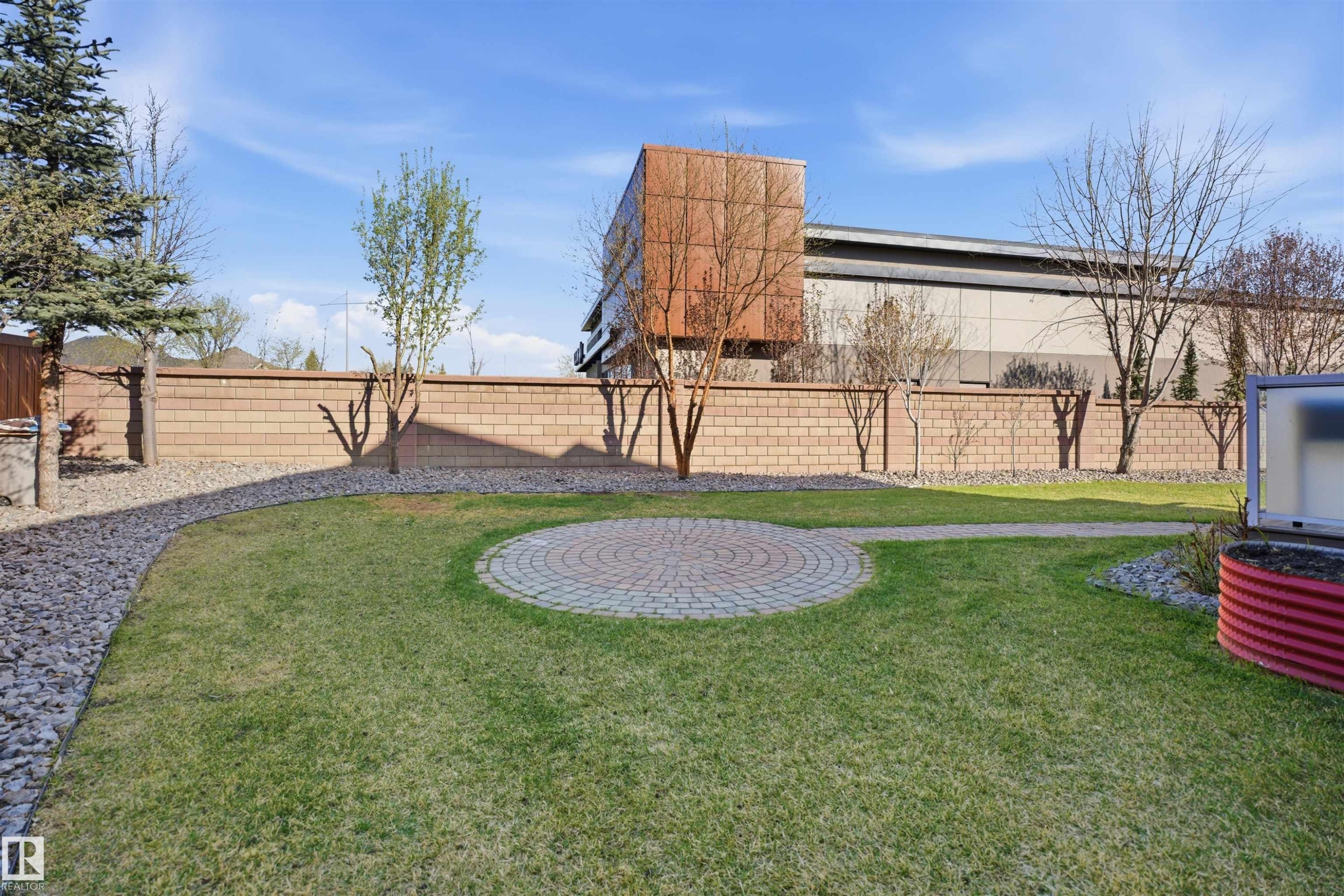 Landscaped backyard featuring a circular paver patio, lush green lawn, and a gravel path - 2256 Cameron Ravine Court, Edmonton, AB - Outdoor