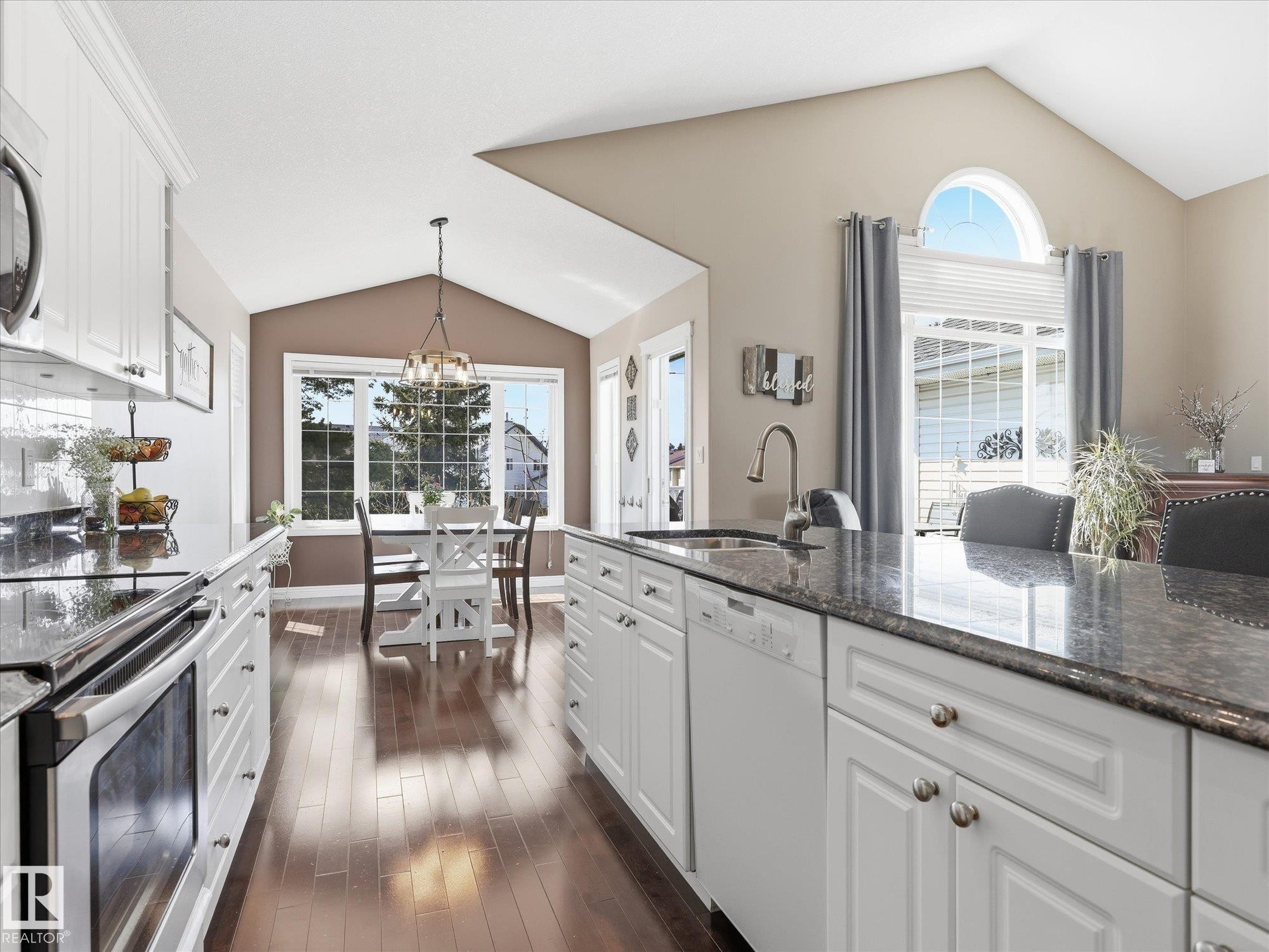 Kitchen featuring an expansive island with a built-in sink, white cabinetry, and dark countertop surfaces - 1340 Oakland Crescent, Devon, AB - Indoor Photo Showing Kitchen With Upgraded Kitchen