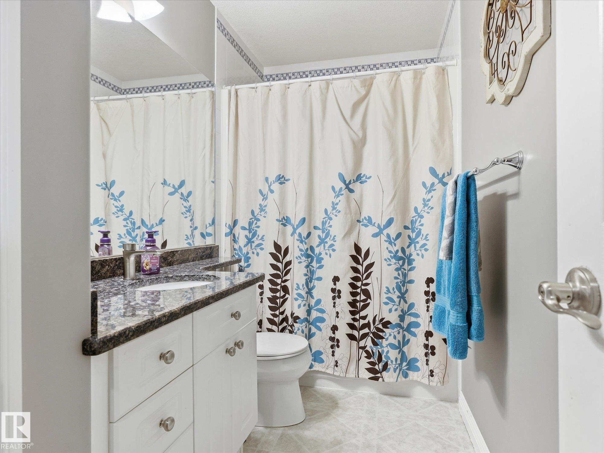 Bathroom featuring a white vanity with an undermount sink, stone-finish countertop, and chrome hardware - 1340 Oakland Crescent, Devon, AB - Indoor Photo Showing Bathroom