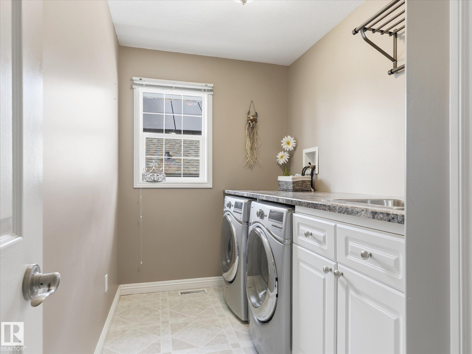 Dedicated laundry area featuring a window, built-in cabinetry, a utility sink, and a countertop - 1340 Oakland Crescent, Devon, AB - Indoor Photo Showing Laundry Room