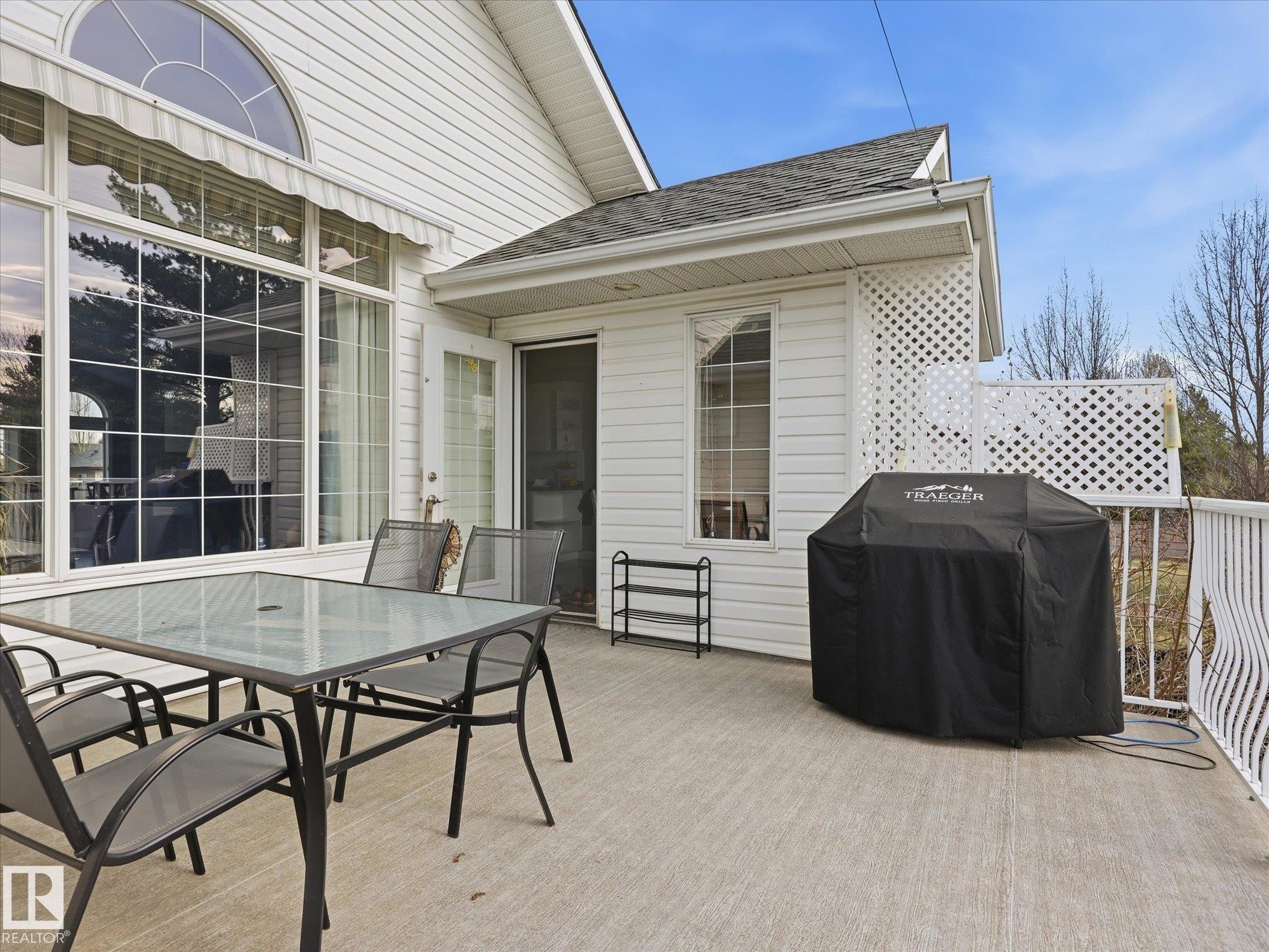 Outdoor deck space featuring a textured concrete surface, white lattice privacy screen, and white railing - 1340 Oakland Crescent, Devon, AB - Outdoor With Deck Patio Veranda With Exterior