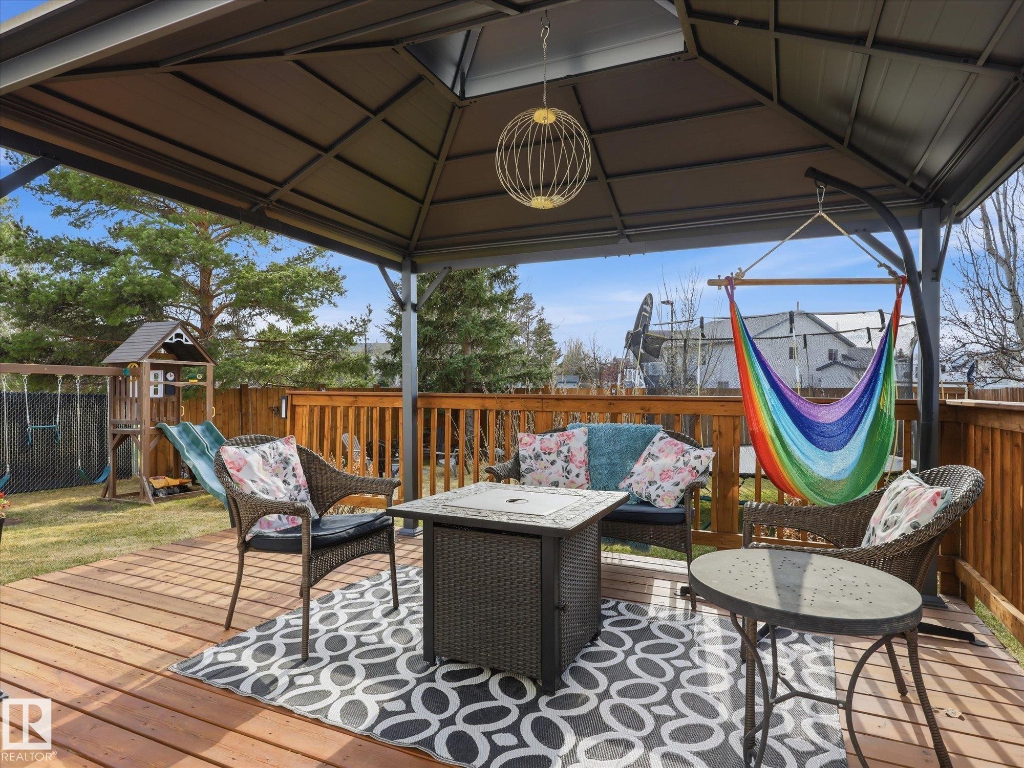Expansive wood-finish deck featuring a metal-frame gazebo, a built-in fire pit, and a wooden privacy fence - 1340 Oakland Crescent, Devon, AB - Outdoor With Deck Patio Veranda With Exterior