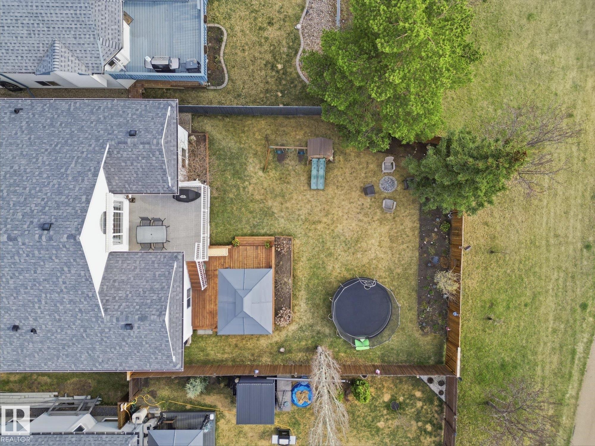 Expansive fenced backyard featuring a large concrete patio, a wood deck with a gazebo, and established perimeter landscaping - 1340 Oakland Crescent, Devon, AB - Outdoor With View