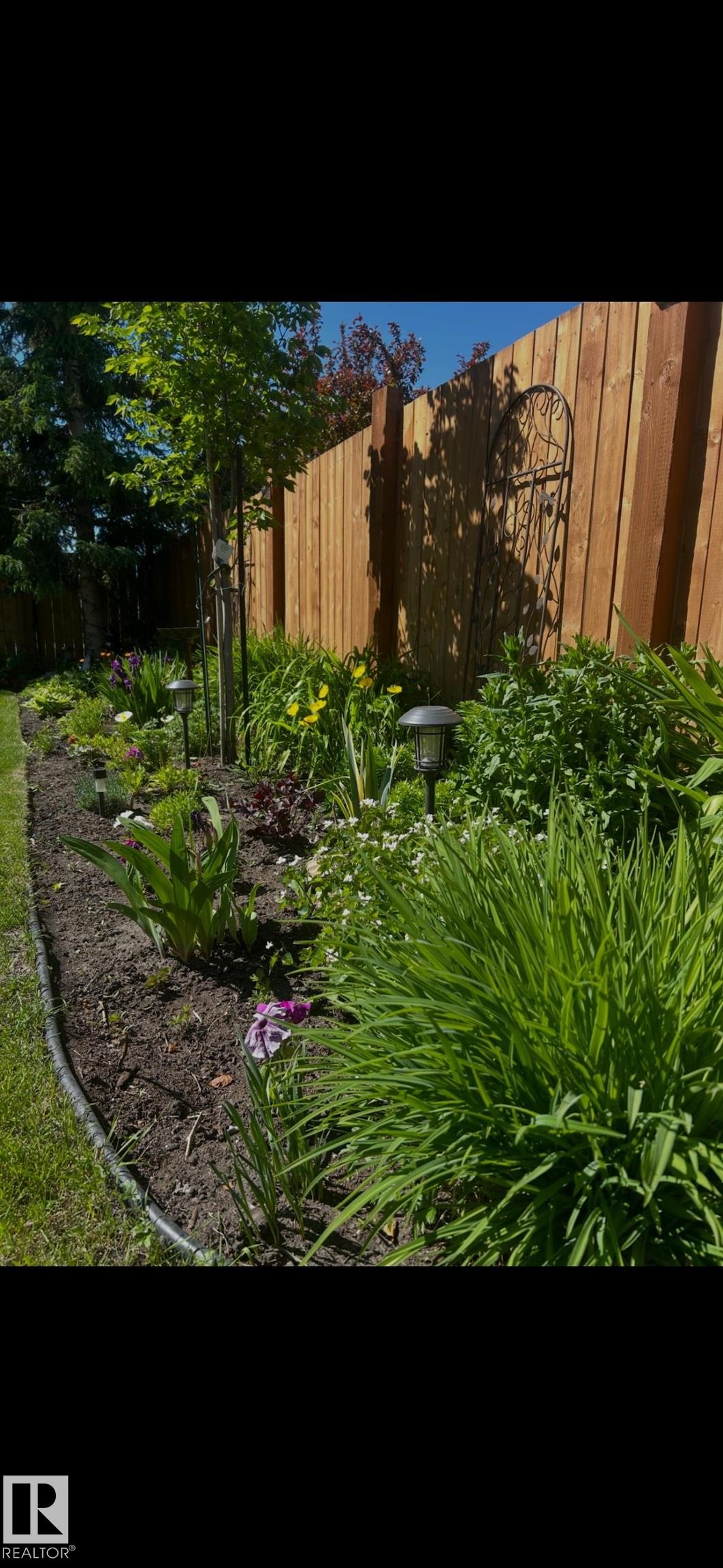 Manicured garden bed featuring diverse plantings, perimeter edging, and integrated path lighting - 1340 Oakland Crescent, Devon, AB - Outdoor