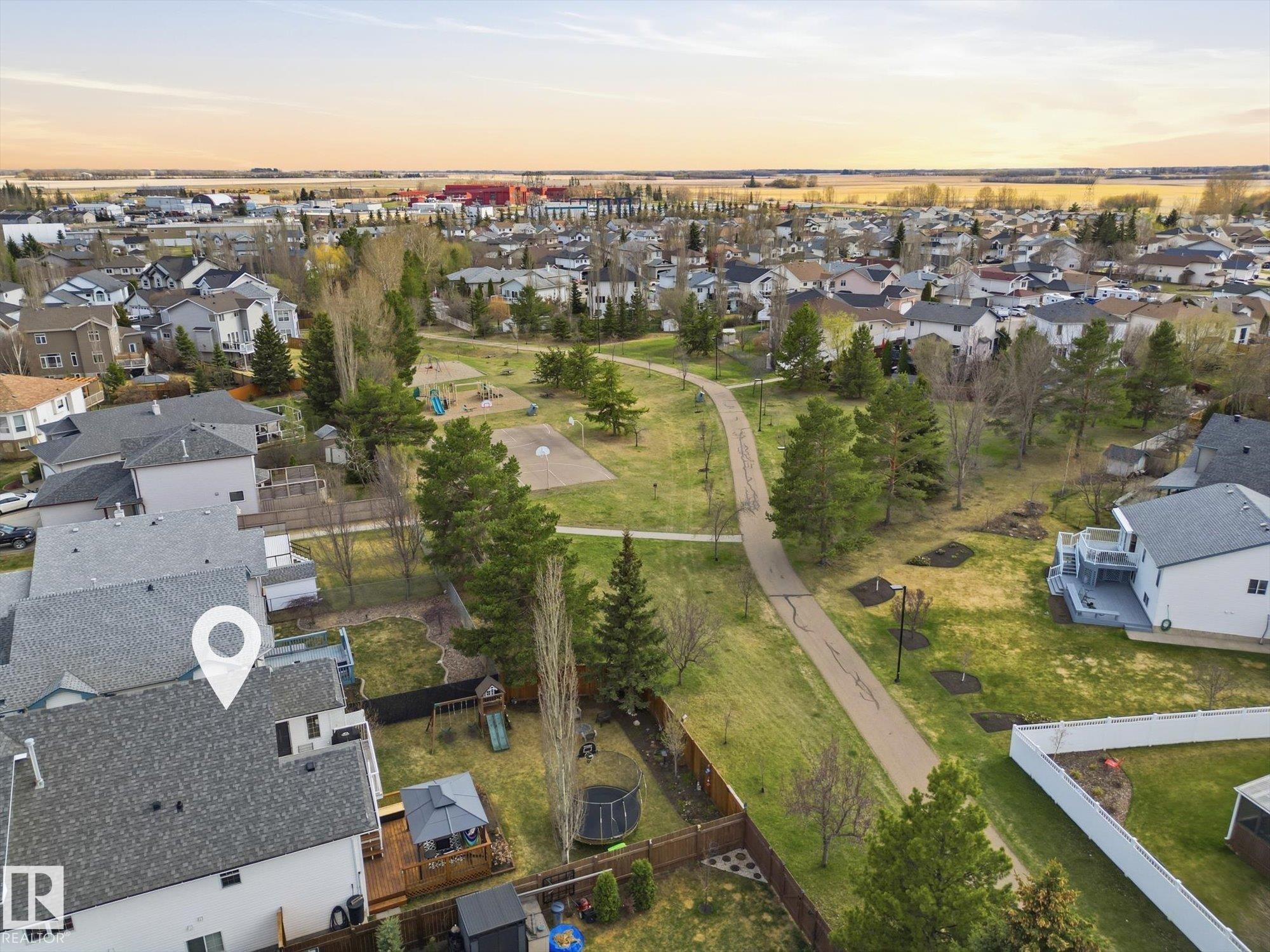 Aerial perspective showcasing a residential neighborhood with a central park featuring a paved walking path, mature trees, and open green spaces - 1340 Oakland Crescent, Devon, AB - Outdoor With View