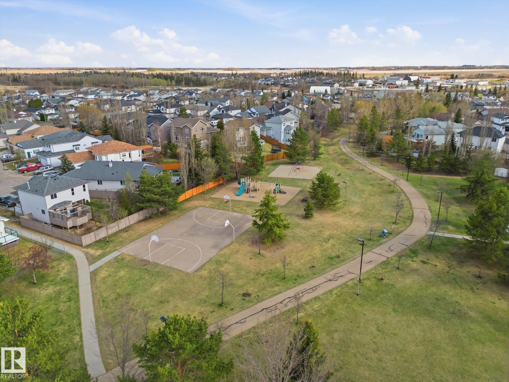 Expansive green space featuring a playground, basketball court, paved walking paths, and mature trees - 1340 Oakland Crescent, Devon, AB - Outdoor With View