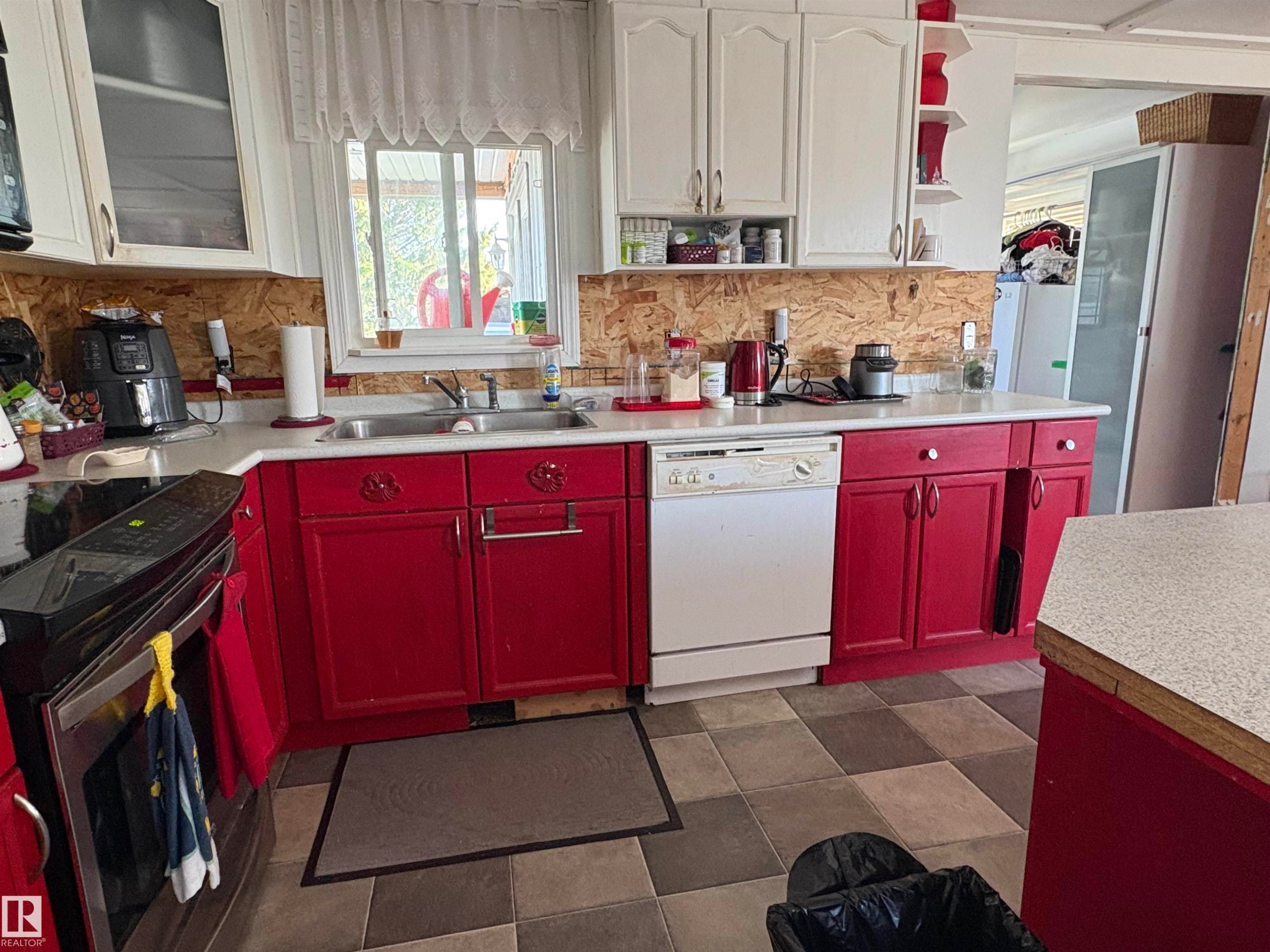 Kitchen featuring red lower cabinetry and white upper cabinetry, a stainless steel sink, a built-in dishwasher, and a tile floor. - 115 2Nd Street E, Derwent, AB - Indoor Photo Showing Kitchen With Double Sink