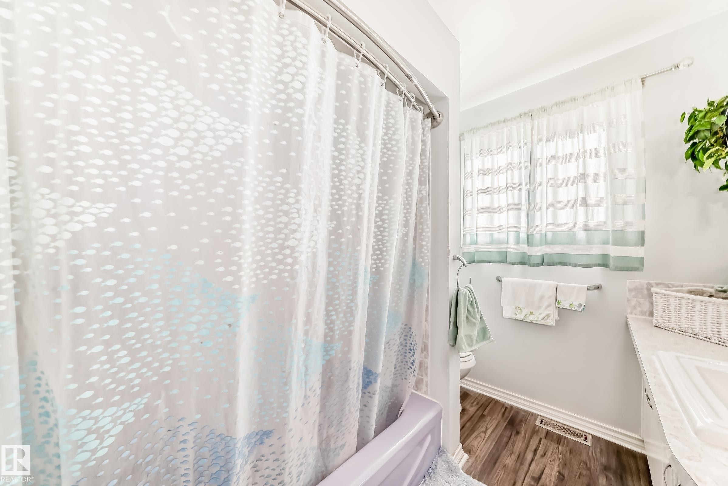 Bathroom featuring wood-finish flooring, a window with horizontal blinds, and a vanity with a white countertop - 3611 108 Street, Edmonton, AB - Indoor Photo Showing Bathroom