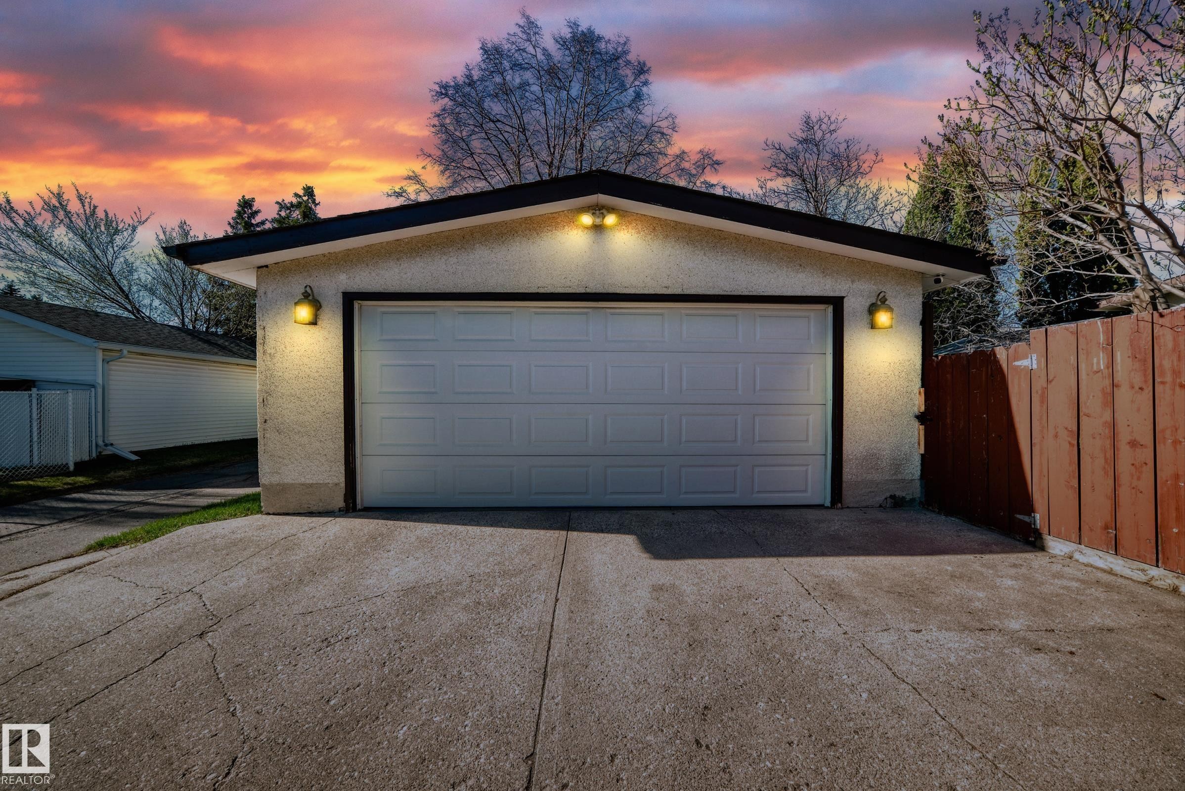 Detached garage featuring a paneled garage door, stucco exterior, and dual exterior sconces - 3611 108 Street, Edmonton, AB - Outdoor