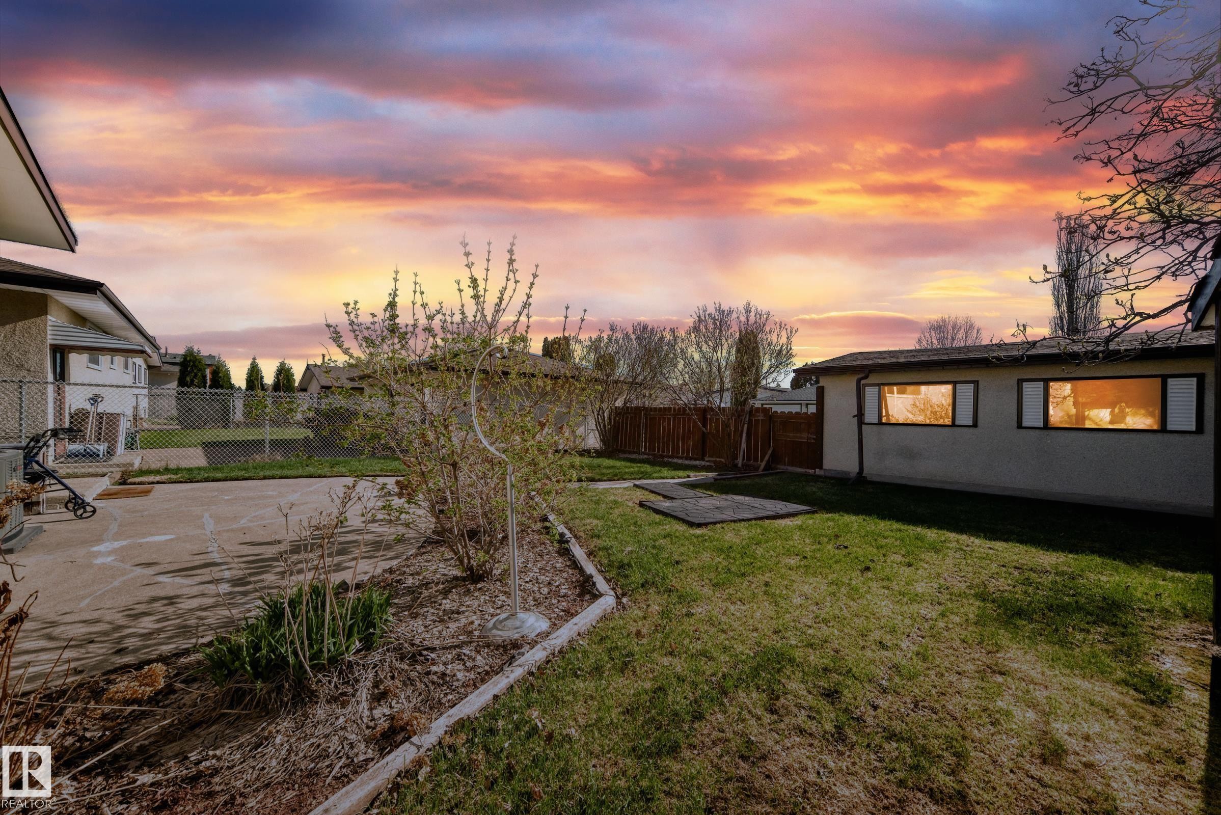 Expansive backyard featuring a concrete patio, established garden beds, and a detached building with multiple windows - 3611 108 Street, Edmonton, AB - Outdoor With View