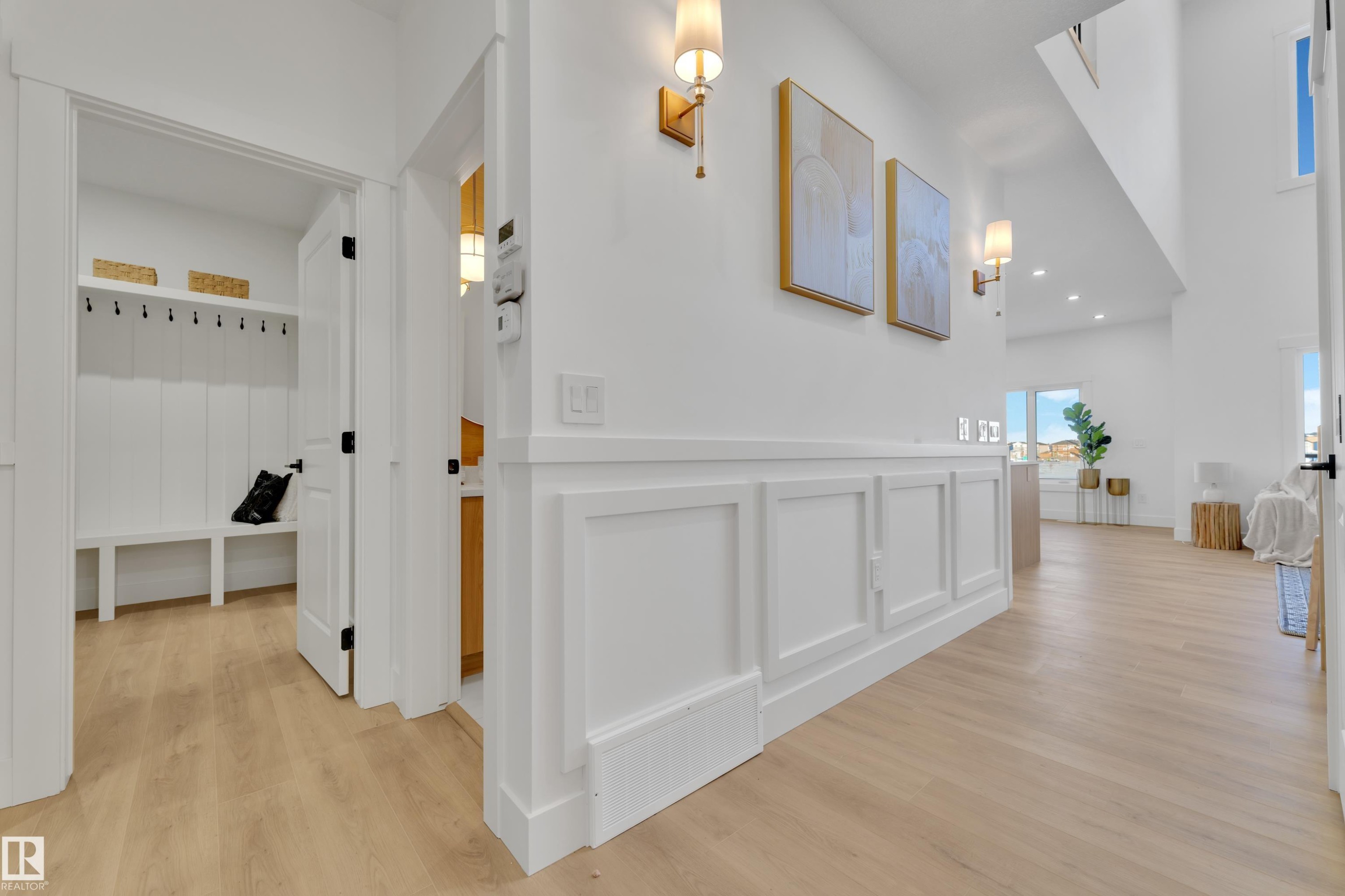 Bright entryway featuring wood-finish flooring, wainscoting, and modern wall sconces - 382 Linden Loop, Leduc, AB - Indoor Photo Showing Other Room