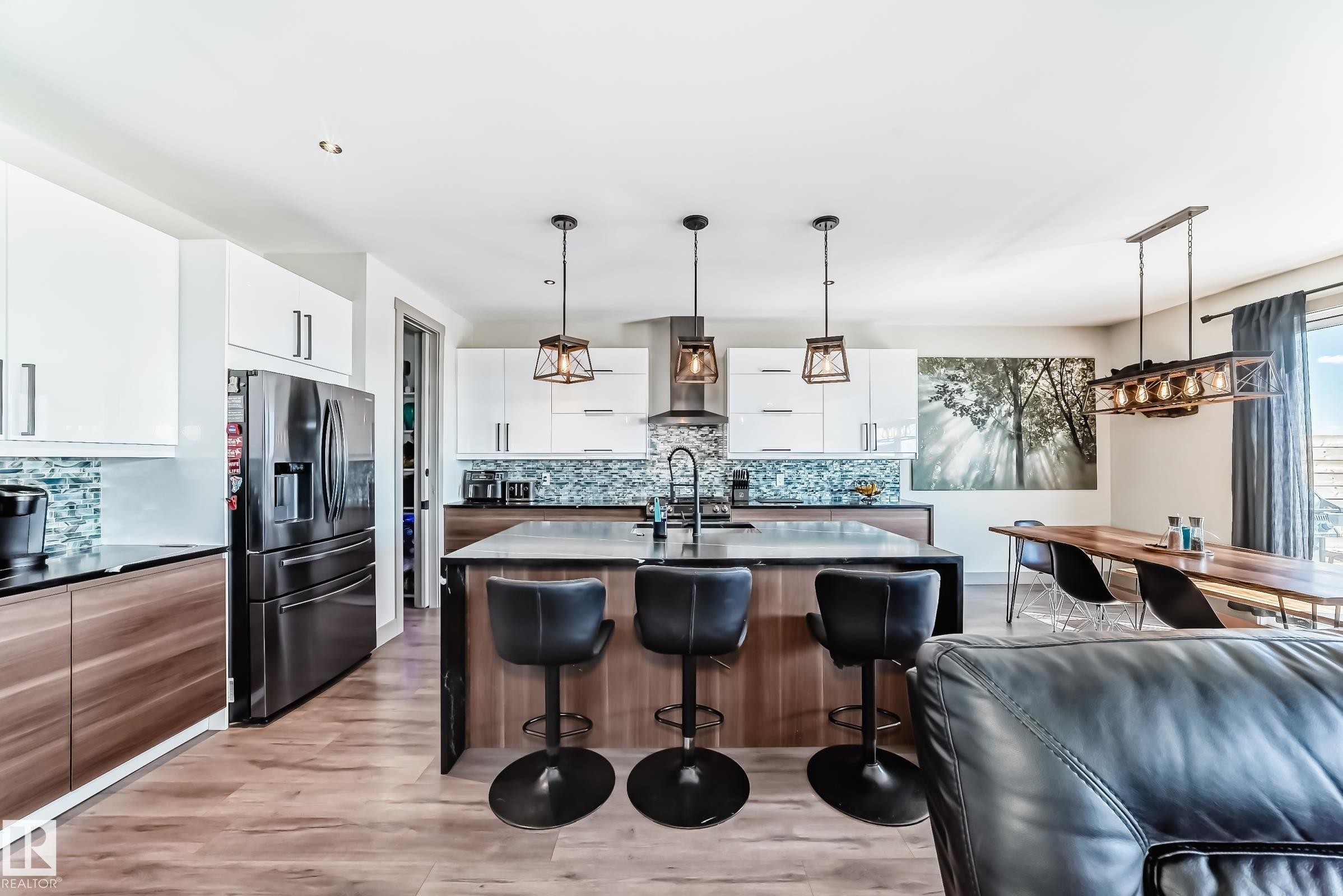 Open-concept kitchen featuring an oversized island with seating, complete with a dark countertop and three pendant lights - 5263 47 Ave, Calmar, AB - Indoor Photo Showing Kitchen With Upgraded Kitchen