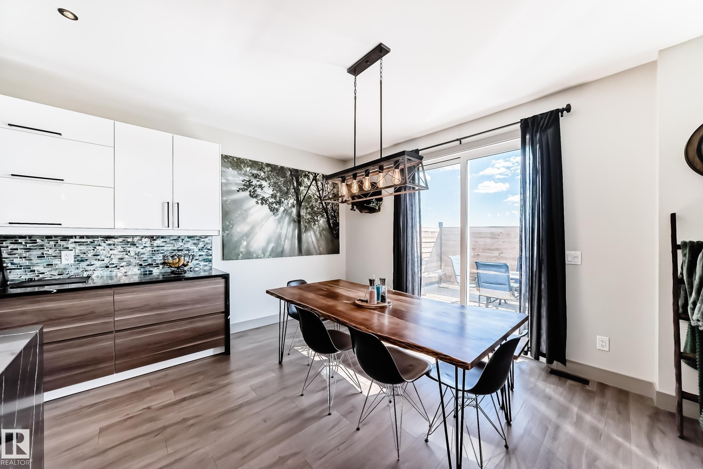 Open concept room featuring wood-finish flooring, a contemporary dining chandelier, and a sliding glass door providing access to an outdoor patio - 5263 47 Ave, Calmar, AB - Indoor Photo Showing Dining Room