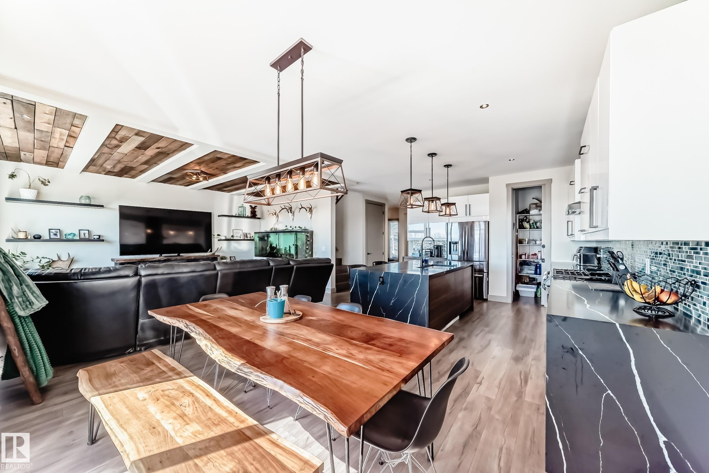 Open-concept living space featuring wood-finish flooring, a kitchen with dark countertops and a mosaic tile backsplash, and a dining area with a live-edge wood table - 5263 47 Ave, Calmar, AB - Indoor Photo Showing Dining Room