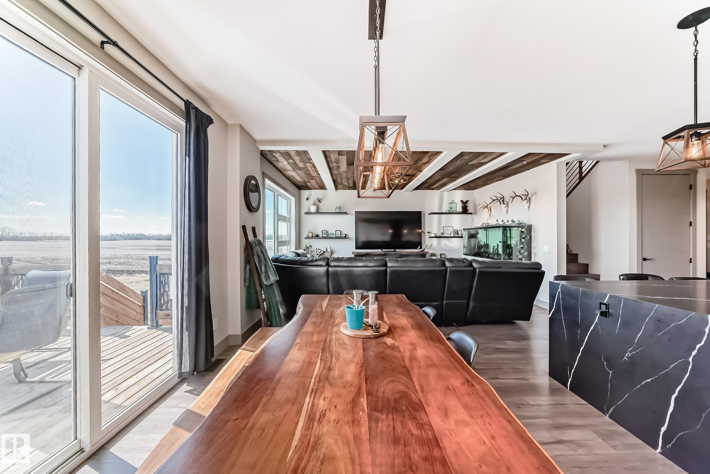 Open-concept living space featuring wood-finish flooring, a large sliding glass door opening to a deck, and exposed beam ceiling details - 5263 47 Ave, Calmar, AB - Indoor Photo Showing Dining Room