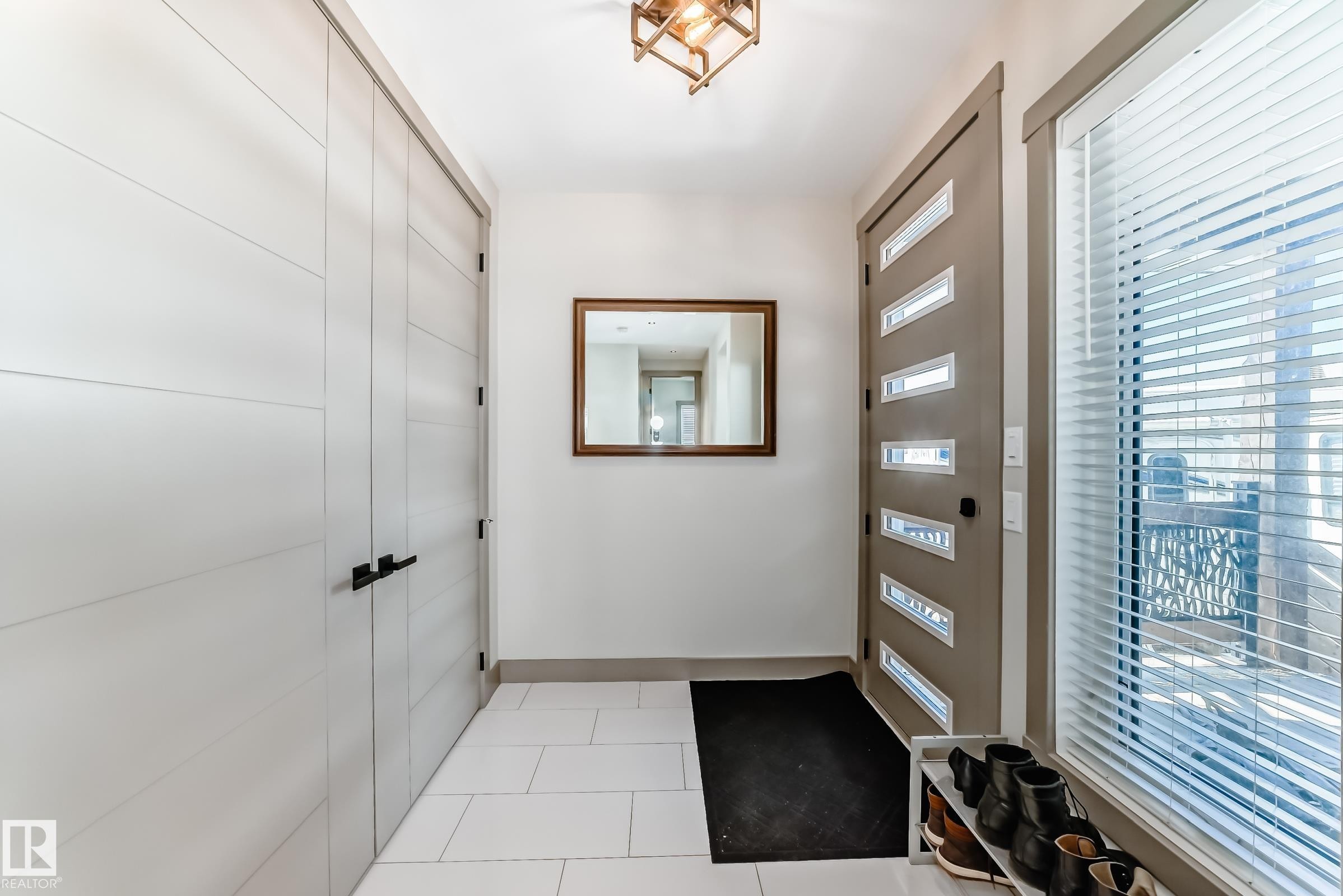 Entryway featuring a modern front door with frosted glass panels, white tile flooring, and a contemporary ceiling fixture - 5263 47 Ave, Calmar, AB - Indoor Photo Showing Other Room