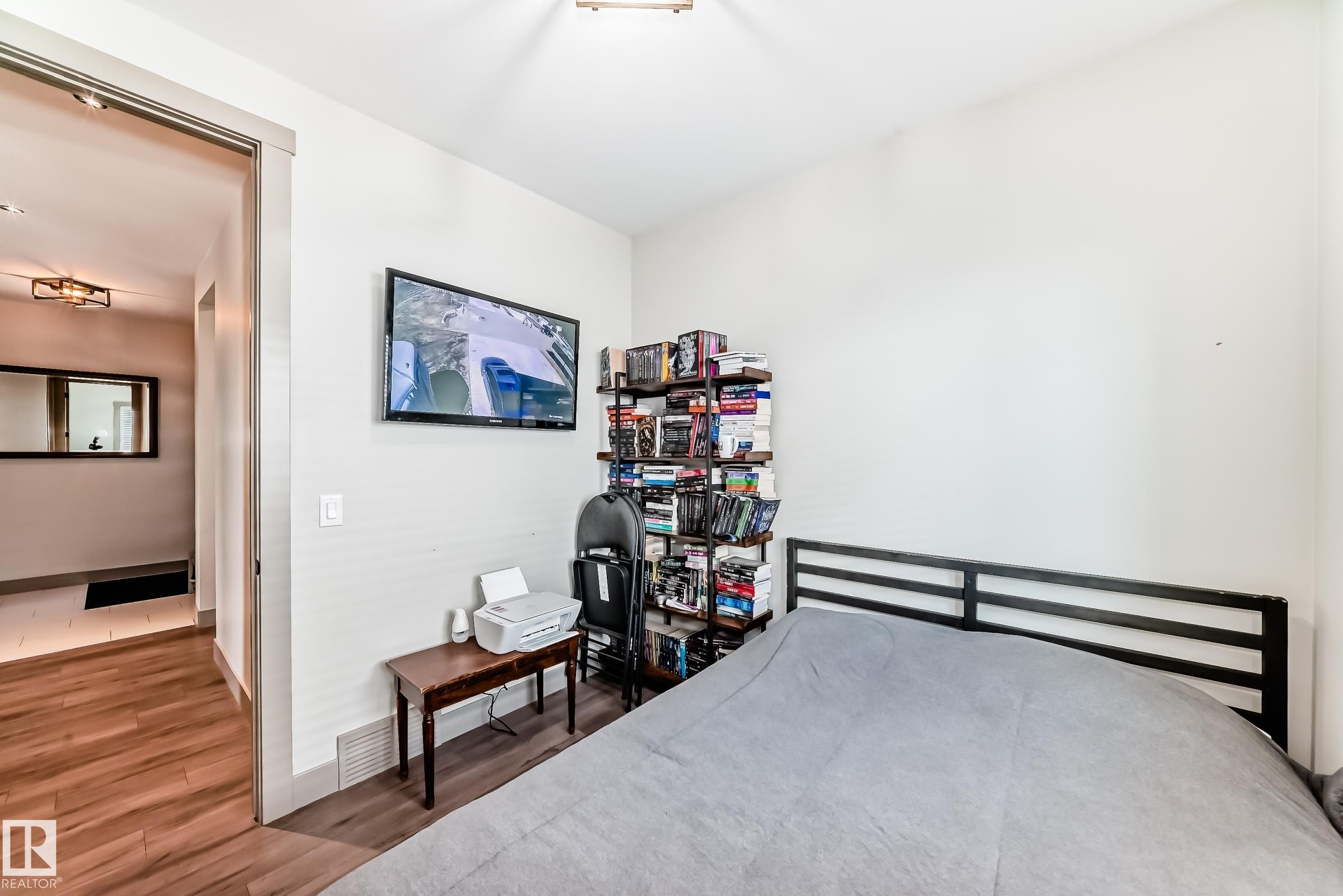 Room featuring wood-finish flooring, a wall-mounted television, and a built-in recessed light fixture in the hallway - 5263 47 Ave, Calmar, AB - Indoor Photo Showing Other Room
