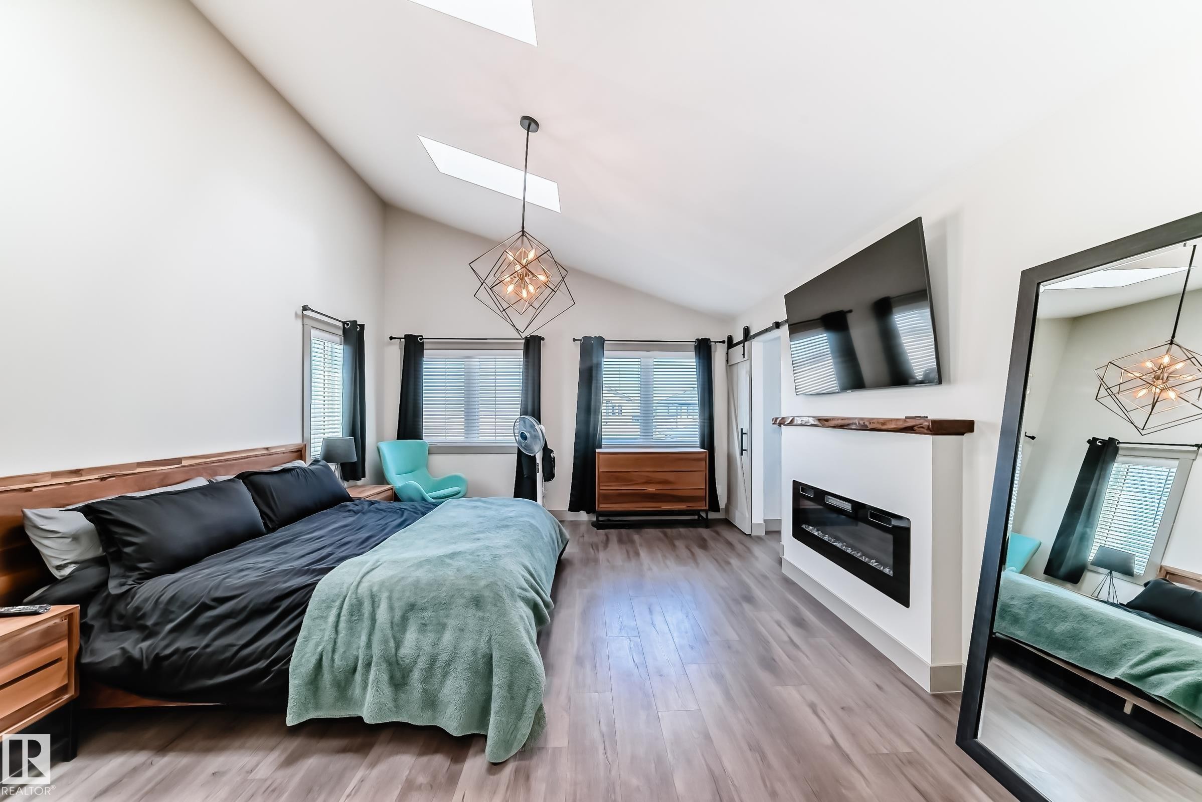 Vaulted ceiling featuring skylights and a geometric chandelier - 5263 47 Ave, Calmar, AB - Indoor Photo Showing Bedroom With Fireplace